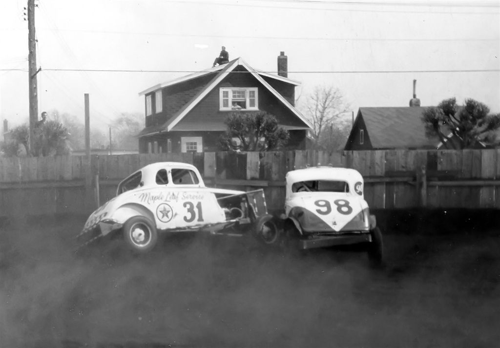 1954. Merv D. and Jim W. tangle in corner #2 with typical cheapskates looking through windows, standing on rooftops or on pickup truck boxes not willing to pay the 25 cents it cost to come in the main gate.  Hundreds of fans did, however, to the most entertaining Wednesday nights I had ever enjoyed as a kid in Fort William, Ontario (now Thunder Bay). View full size.