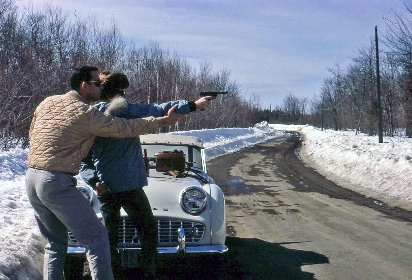 My father showing my mother how to shoot his Luger pistol when they were a new couple. This is on the road to the Old Town side of Pushaw Lake in Maine with the bog road in the background. This road used to flood every spring. That's dad's 1960 Triumph TR3. Wish he had kept it. View full size.