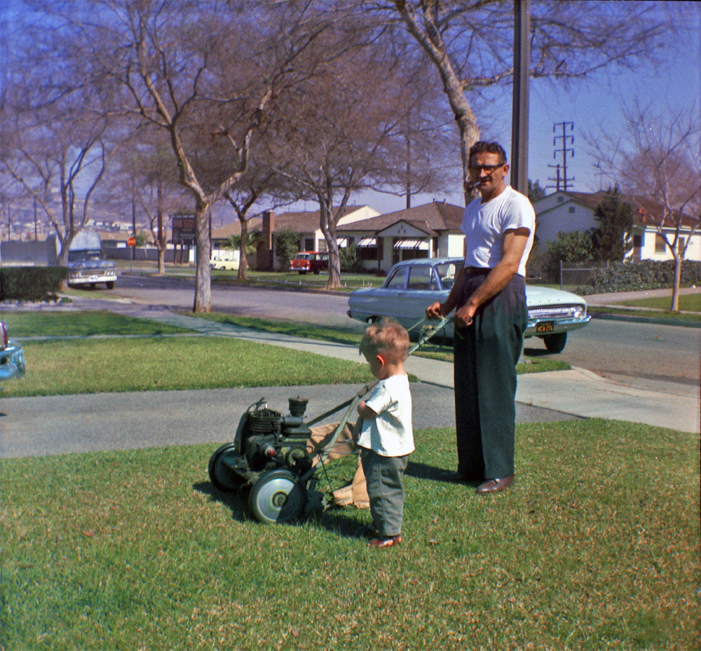 Mowing the lawn was a family experience back then. I really like the car in the back (I'm not a car enthusiast. What kind of car is that?). Why don't cars come in that color anymore? It's kind of funny because the little kid, my father, later grew up to become a chief engineer on tuna boats. This was taken in L.A., early '60s. Scanned from a Kodak safety negative. View full size.