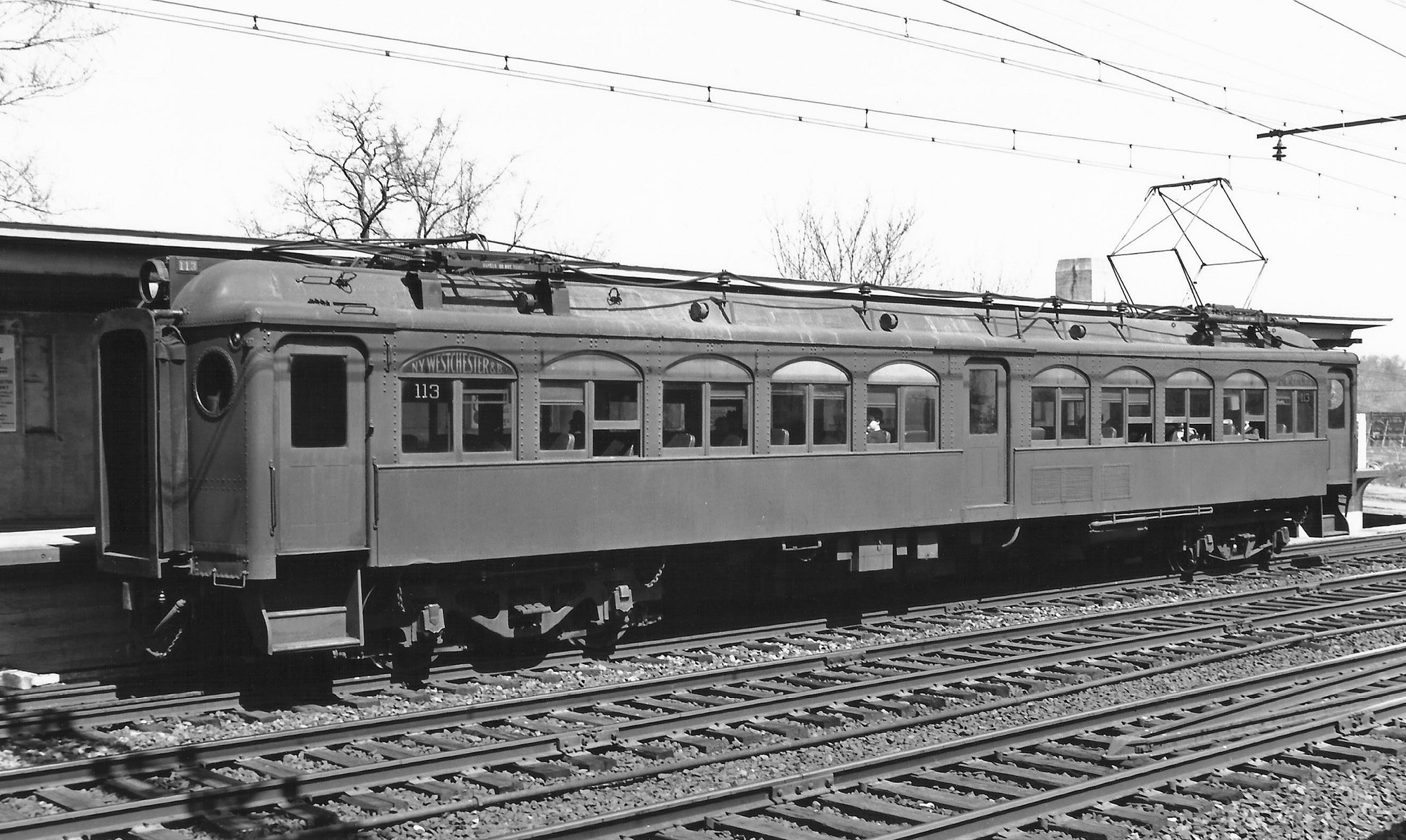 Pictured is a multiple unit electric passenger car of the New York, Westchester and Boston Railway at the Baychester Avenue Station, Bronx New York in May of 1937. “The Westchester” as it was known locally was a rapid transit system that linked the Bronx with White Plains to the north of New York City and subsequently Port Chester to the east. At the time of the railway's construction in 1912, the NYW & B was one of the most advanced systems in the world with state of the art equipment, signaling, overhead power supply and exquisite stations of masonry and concrete in both the Italian Renaissance and Mission architectural styles. The NYW & B ceased operation in late 1937, a victim of The Great Depression, the emerging popularity of the automobile and mismanagement of its parent company, the New Haven Railroad. View full size.