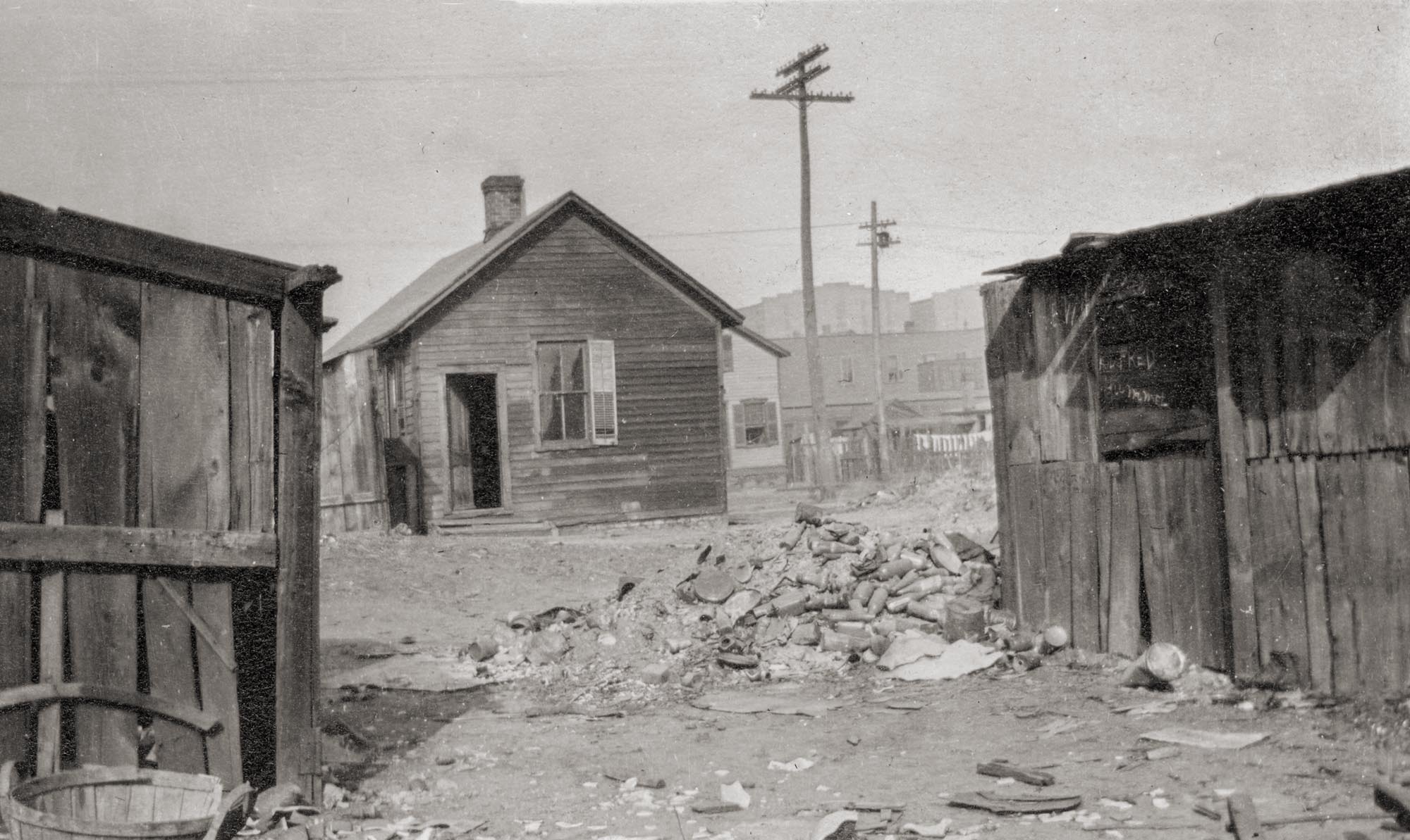 The slums at Cinder Point between the Railroad and Illinois River, at the foot of Sanger Street, nearby the Flatboat City locale, Peoria, Illinois, circa mid-1930s. The Hiram Walker & Sons Distillery plant can be seen in the background. Picture taken by an unknown employee of the Neighborhood House social service agency, which delivered meals to kids and the elderly. 

Neighborhood House Association, 1020 S. Matthew, Peoria IL, established in 1896, is dedicated to providing a Safe Haven with comprehensive services that meet the social, emotional and material needs of individuals and families from infancy to the elderly.