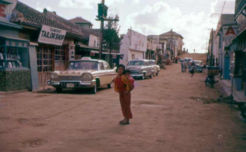 An Okinawa street scene from approximately 1957. The village is called Futenma (aka Fatima). This image is from one of my Dad's badly faded Ektachrome slides. View full size.
