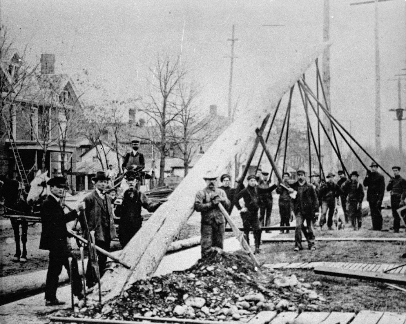 Workers piking a pole into place. Location and date unknown. View full size.