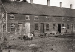 September 1911. "Crowded tenement used by cranberry pickers ('Bravas' or 'black Portuguese,' from the islands of Cape Verde) in bogs near Wareham, Massachusetts." Gelatin silver print by Lewis Wickes Hine. View full size.
Toys for poor kids?Reminds me of the barnyard in Croatia 30 years ago where my 3-year-old nephew's favorite toy was a live chicken. He'd grab one and hang on for dear life. Great fun. ("You'd be wise to leave that big rooster alone.") 
Still plenty of bogsThere are still many bogs in the area. When I was a younger lots of us kids got part time jobs picking cranberries. It's quite interesting to see the bogs raked and flooded and the cranberries collected. Ocean Spray's headquarters were in this area of Massachusetts.
Amazing!Here we see replicated many of the conditions of an inner-city tenement block in what otherwise was probably a very bucolic setting.
(The Gallery, Kids, Lewis Hine)