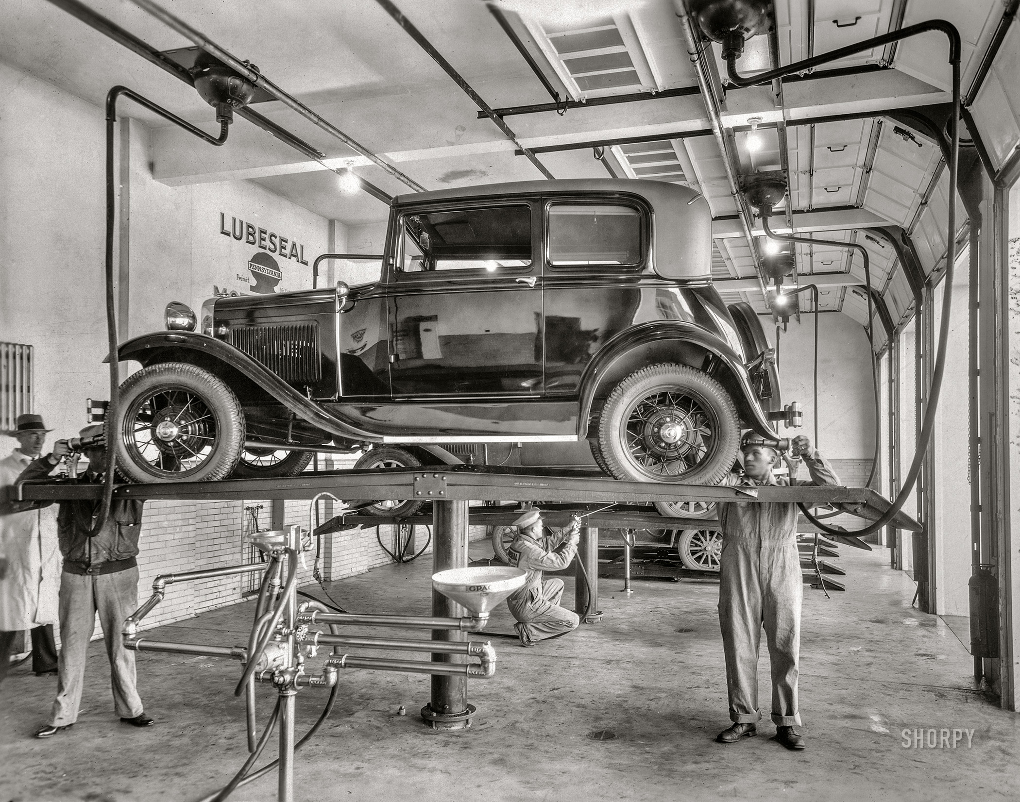 Circa 1930. "Ford Model A on lubrication rack at Lubeseal service garage." View full size.
