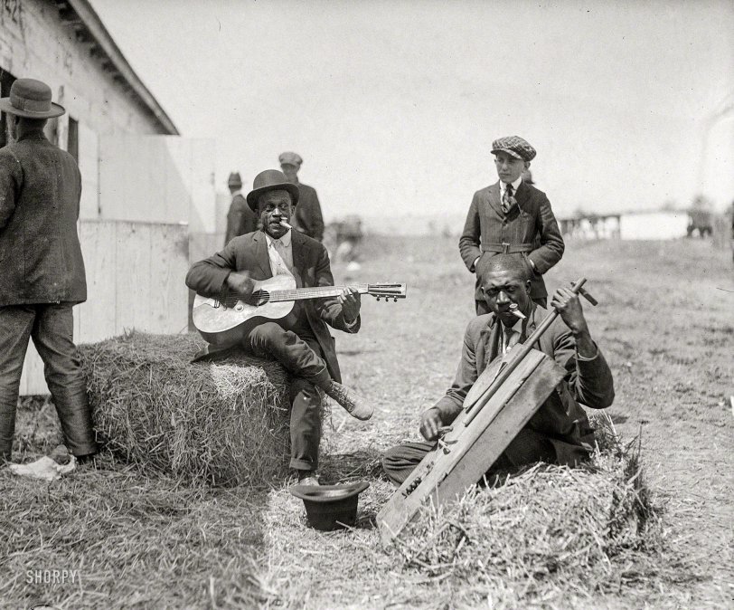 Washington, D.C., circa 1920. "Characters" is all they wrote on the label of this National Photo glass negative. Library of Congress annotation: "Photograph shows two  African American men sitting on bales of hay and playing instruments outside a barn or stable. One man plays guitar and the other plays a bowed instrument similar to a cello; both men simultaneously play kazoos." View full size.
