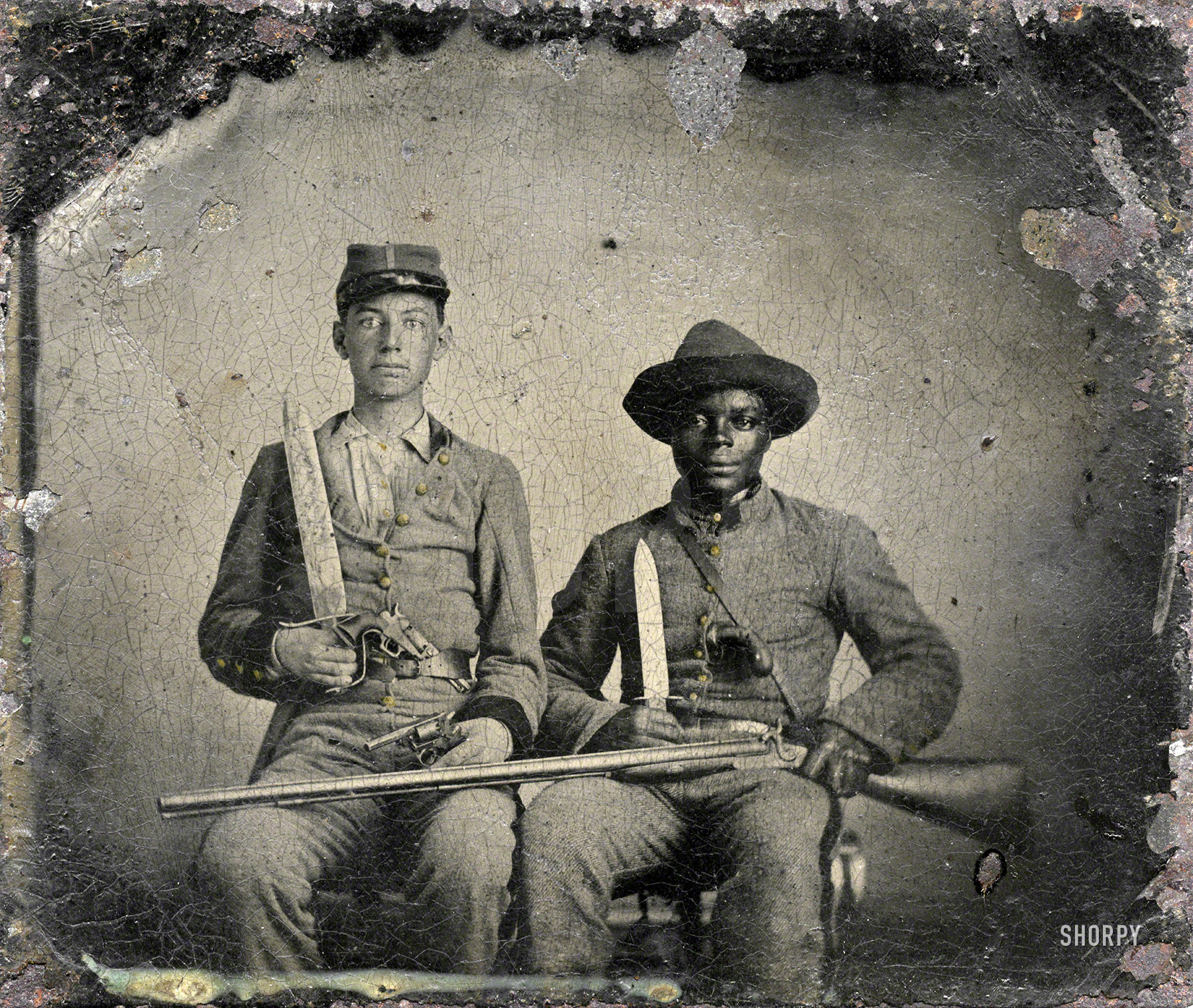 &nbsp; &nbsp; &nbsp; &nbsp; In 1861, A.M. Chandler enlisted in the Palo Alto Confederates, which became part of the 44th Mississippi Infantry Regiment. His mother, Louisa Gardner Chandler, sent Silas, one of her 36 slaves, with him. On Sept. 20, 1863, the 44th Mississippi was engaged in the Battle of Chickamauga, where Chandler was wounded in his leg. A battlefield surgeon decided to amputate but, according to the Chandler family, Silas accompanied him home to Mississippi where the limb was saved. His master's combat service ended as a result of the wound but Silas returned to the war in January 1864 when A.M.'s younger brother, Benjamin, enlisted in the 9th Mississippi Cavalry Regiment. (See also: A Slave's Service in the Confederate Army.
"Sergeant A.M. Chandler of the 44th Mississippi Infantry Regiment, Co. F., and Silas Chandler, family slave, with Bowie knives, revolvers, pepper-box, shotgun, and canteen." Handwritten label on back of frame: "Andrew Martin Chandler, born 1844, died 1920. Servant Silas Chandler. 44th Mississippi Regiment, Col. A.K. Blyth. Wounded in battle of Chickamauga." View full size.