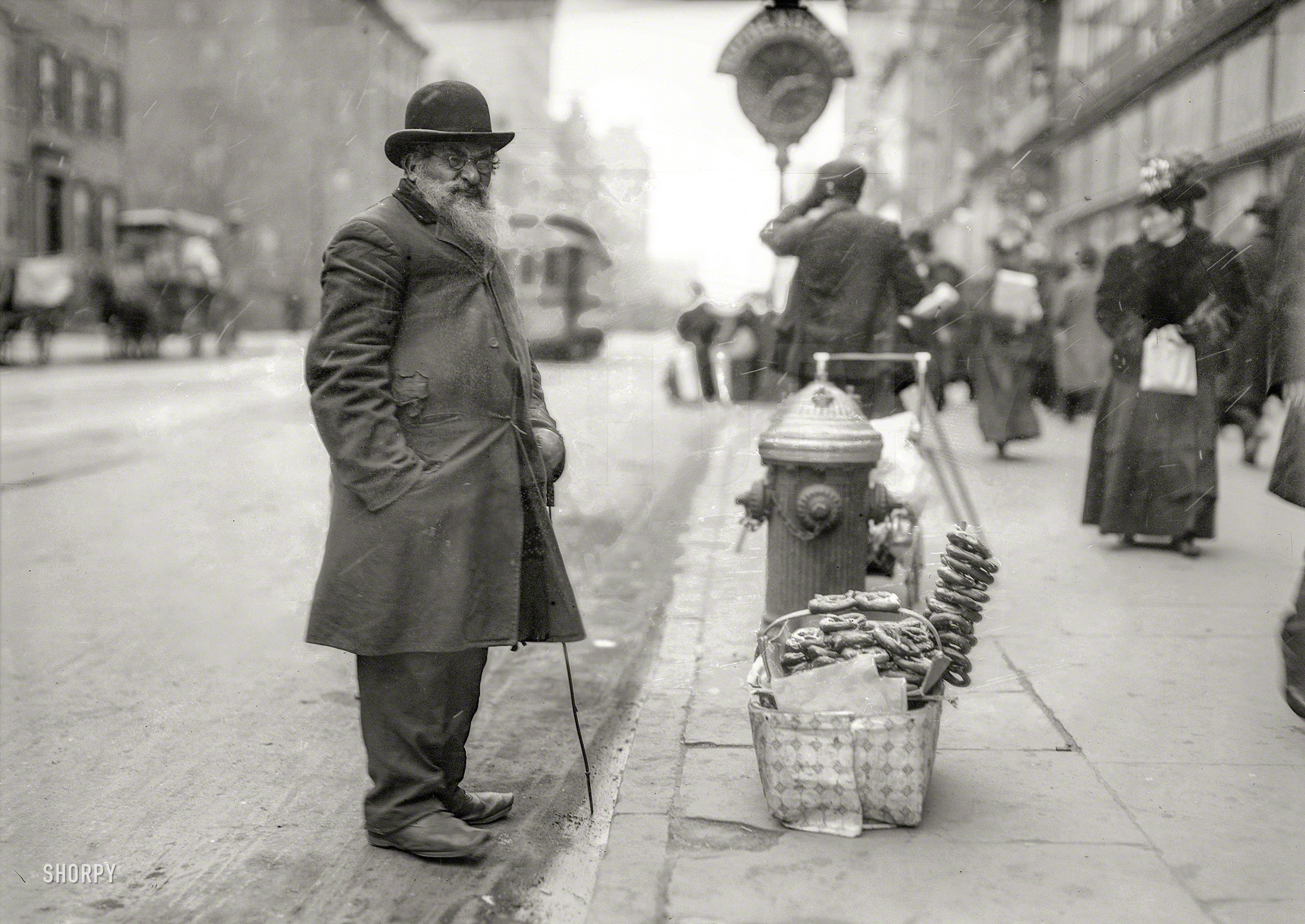 New York circa 1910. "Seller of pretzels, Sixth Avenue." With a dusting of salt and snow. 5x7 glass negative, George Grantham Bain Collection. View full size.