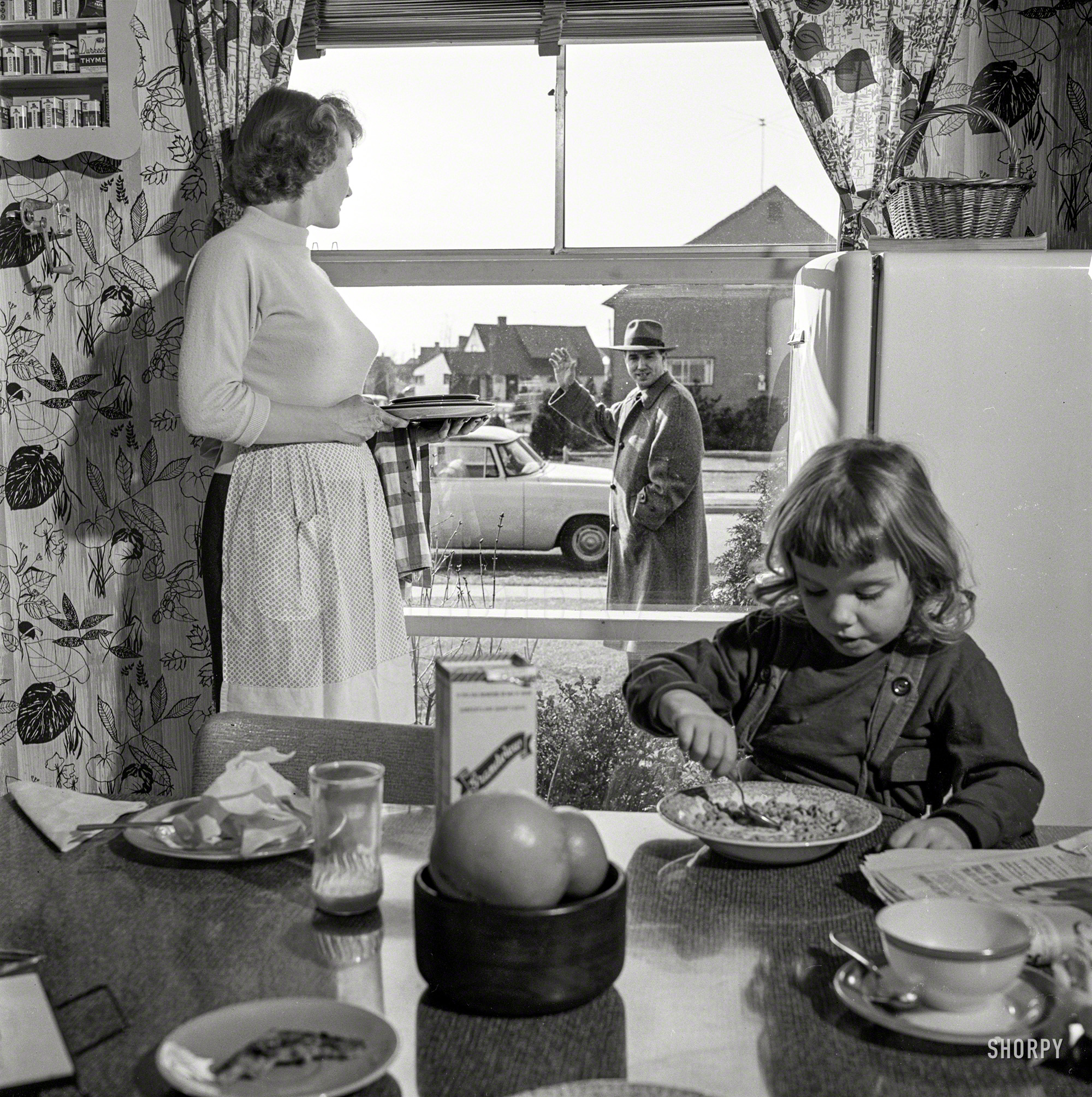 March 1955. "Men participating in family life. Includes women and children standing by window waving to men as they leave for work." Photo by Bob Lerner for the Look magazine assignment "Male Behavior." View full size.