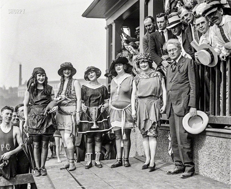 
Lansburgh Girls Win Style Prize
Five Models Gain Cup at
Tidal Bathing Beach Costume Show.
&nbsp; &nbsp; &nbsp; &nbsp; With five models displaying the most modern bathing costumes, Lansburgh &amp; Brother won the prize cup at the first annual style show, held yesterday afternoon at the Tidal bathing beach. The models who represented Lansburgh's -- all local girls -- were Mary Lee, Iola Swinnerton, Thelma Spencer, Hattie Spencer and Julia Cunningham. The suits which they wore were special importations, brought to Washington for exhibition at this show ...
 -- Washington Post, 6/26/1921

Washington, D.C., 1921. "Bathing Beach costume contest." At left we have Iola Swinnerton, First Lady of Shorpy in perpetuum; the others are plebeian ciphers spared total invisibility only by the grace of her luminous beauty. View full size.
