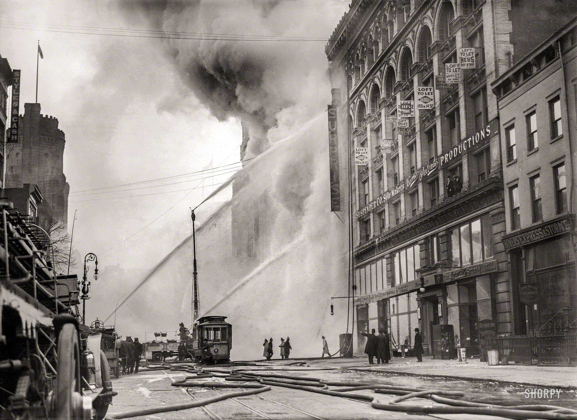December 20, 1909. "Firemen spraying burning building on West 14th Street, New York." 5x7 glass negative, Bain News Service. View full size.
&nbsp; &nbsp; &nbsp; &nbsp; Three million gallons of water from the high-pressure mains were pumped into a fire that destroyed a large seven-story factory and loft building at 180-188 West Fourteenth Street yesterday morning, and for five hours the fire, which raged until the afternoon, completely cut off traffic on that street. The pavement and sidewalks and many buildings for almost a block were coated with thick mid-Winter ice. Fire and water together provided a spectacle for thousands of Christmas shoppers who crowded both sides of the street.
&nbsp; &nbsp; &nbsp; &nbsp; Although there were no injuries from the fire, it caused damage of $200,000. Workers at the training school of the Salvation Army headquarters, adjoining the building on the east, were routed from their beds. It is not known what started the fire.
-- New York Times, 12/21/1909