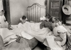 November 1912. New York. "Family cutting embroidery in tiny crowded bed-room. (For complete details see Miss E.C. Watson's report.)" Glass negative by Lewis Wickes Hine for the National Child Labor Committee. View full size.
