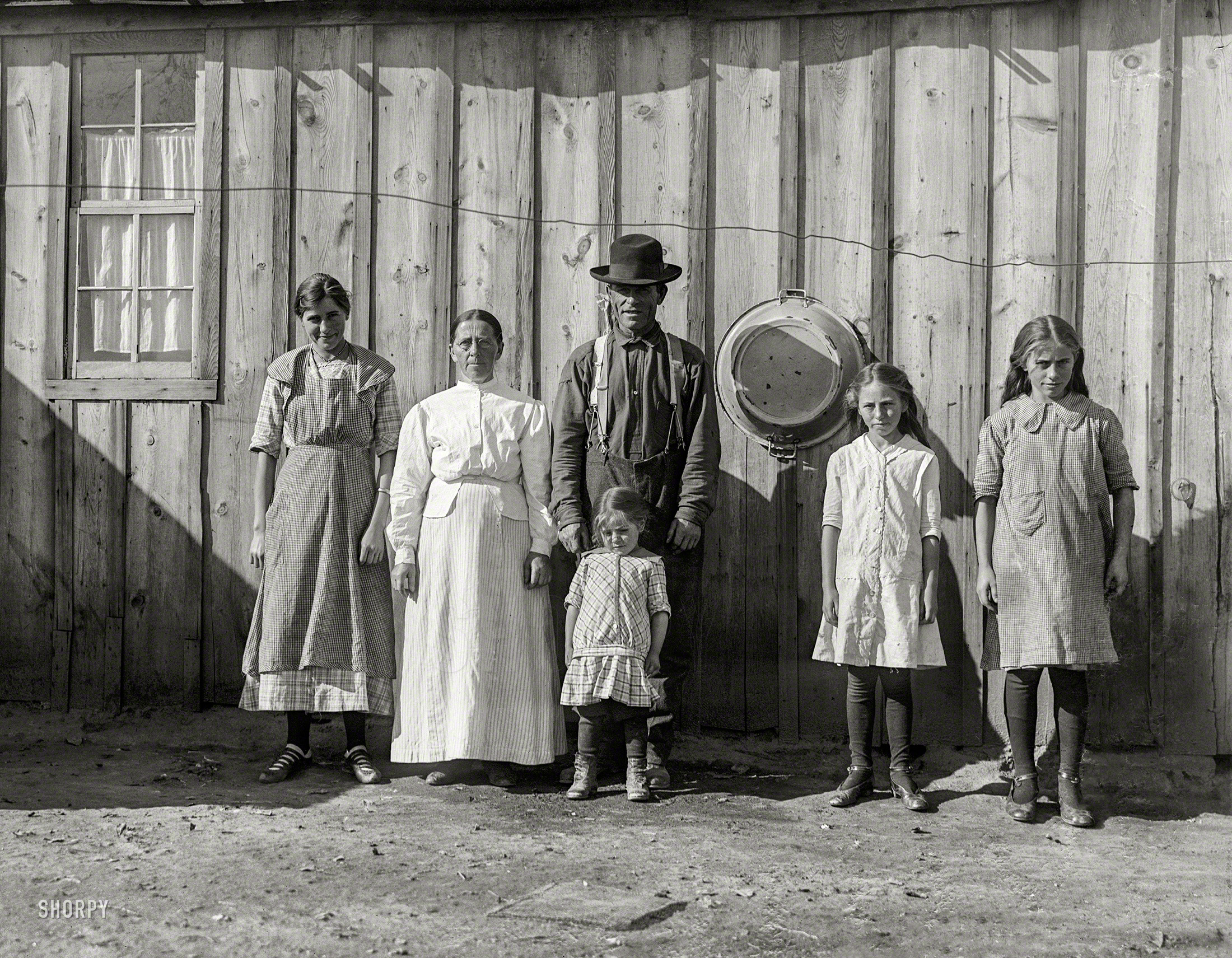 Oct. 30, 1915. Fort Collins (vicinity), Colorado. "A case of 'Economic Need.' Jacob Rommel and his family live in this roomy shack, well-furnished, with a good range, organ, etc. They own a good home in Fort Collins, but late in April they moved out here, taking contract for nearly 40 acres of beets, working their 9- and 10-year-old girls hard at piling and topping (although they are not rugged) and they will not return until November. The little girl said, 'Piling is hardest, it gets your back. I have cut myself some, topping.' The older girl said, 'Don't you call us Russians, we're Germans' (although most of them were born in Russia). Family been in this country eleven years." Glass negative by Lewis Wickes Hine. View full size.