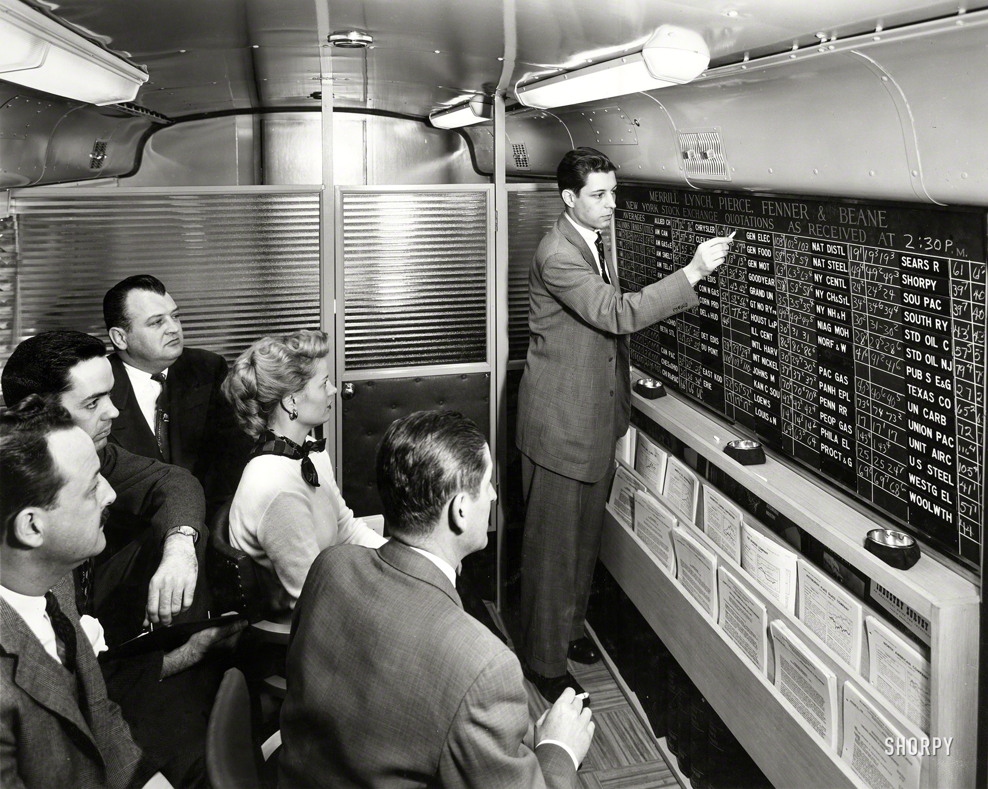 &nbsp; &nbsp; &nbsp; &nbsp; So how does the account exec know what the prices are?
1954. "Merrill Lynch account executive chalks up current stock prices on quotation board in firm's new mobile office." One of the earlier mobile apps. View full size.