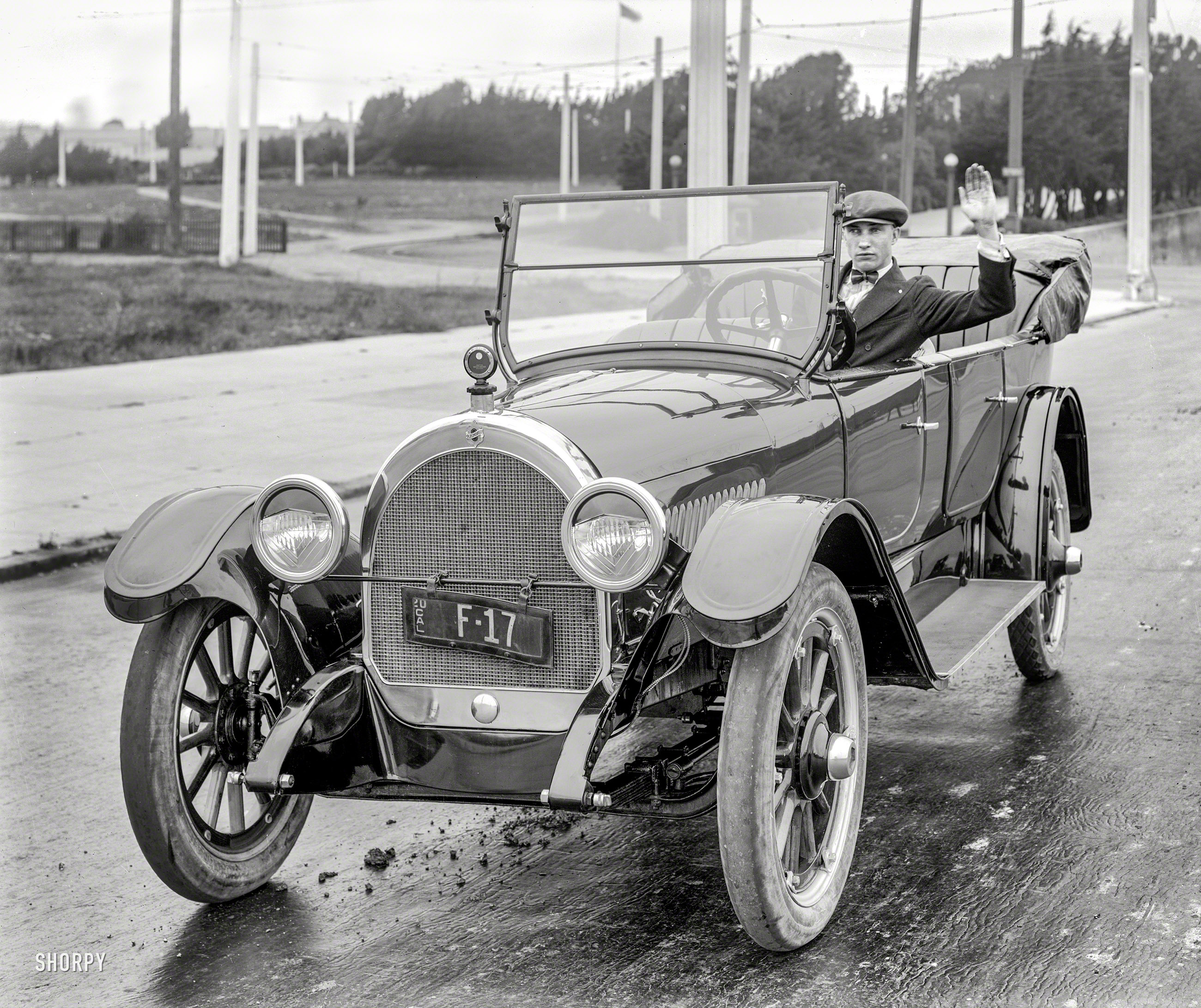 San Francisco in 1920. "Oldsmobile touring car." Its dapper driver signaling either "hello" or a right turn. 5x7 glass negative by Christopher Helin. View full size.