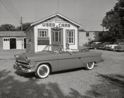 The Rucker Oldsmobile used car lot in Columbus, Georgia, presents this shiny Ford Crestline convertible (low miles, California car) for your consideration, if a Rucker Rocket is not your thing. 4x5 inch acetate negative from the Shorpy News Photo Archive. View full size.