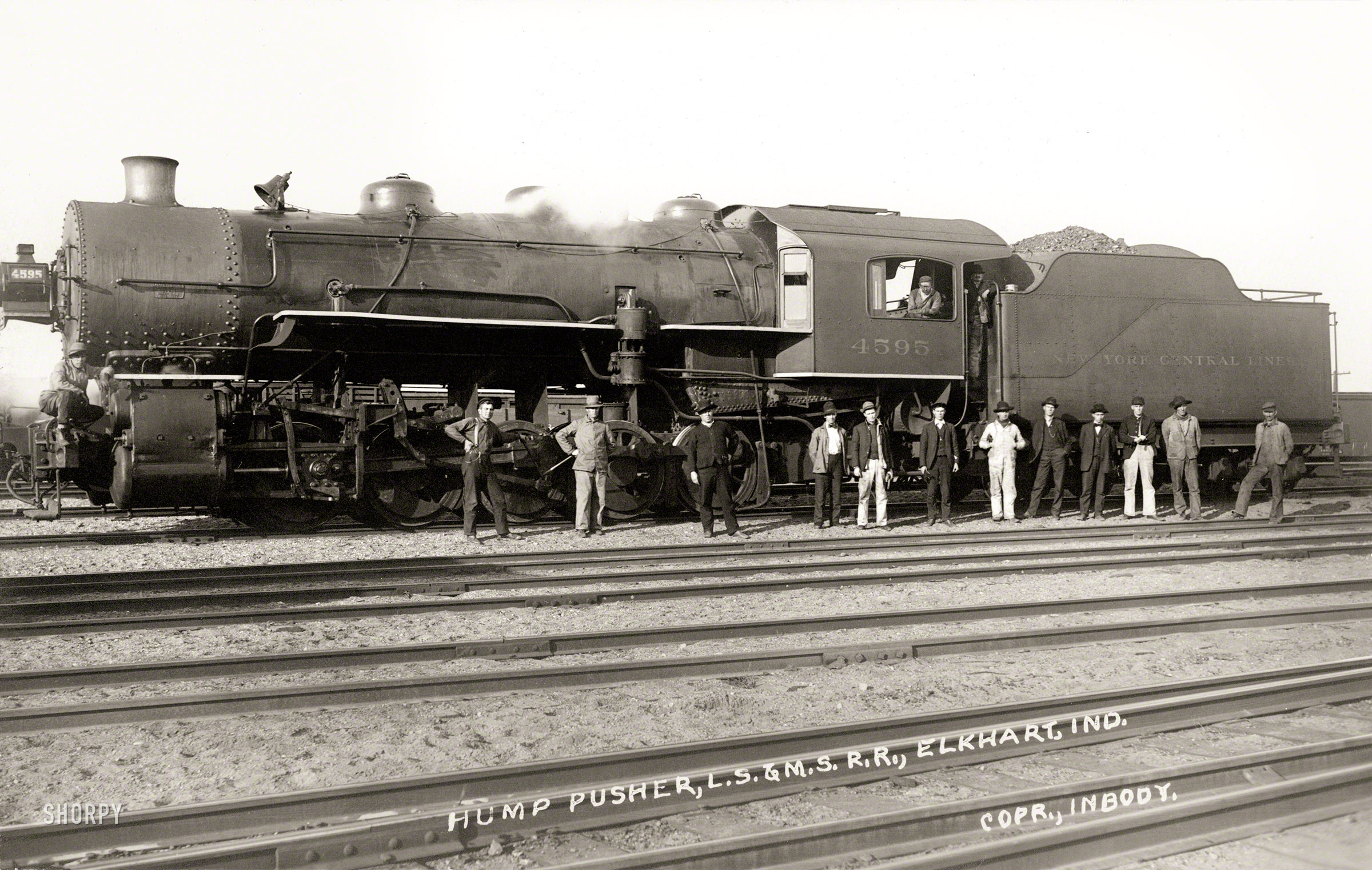 August 19, 1912. "Hump pusher, L.S. & M.S. R.R." On verso: "Made by J. Inbody, Elkhart, Indiana. Home Phone 500." A postcard showing trainmen of the Lake Shore & Michigan Southern Railway and Locomotive 4595. View full size.