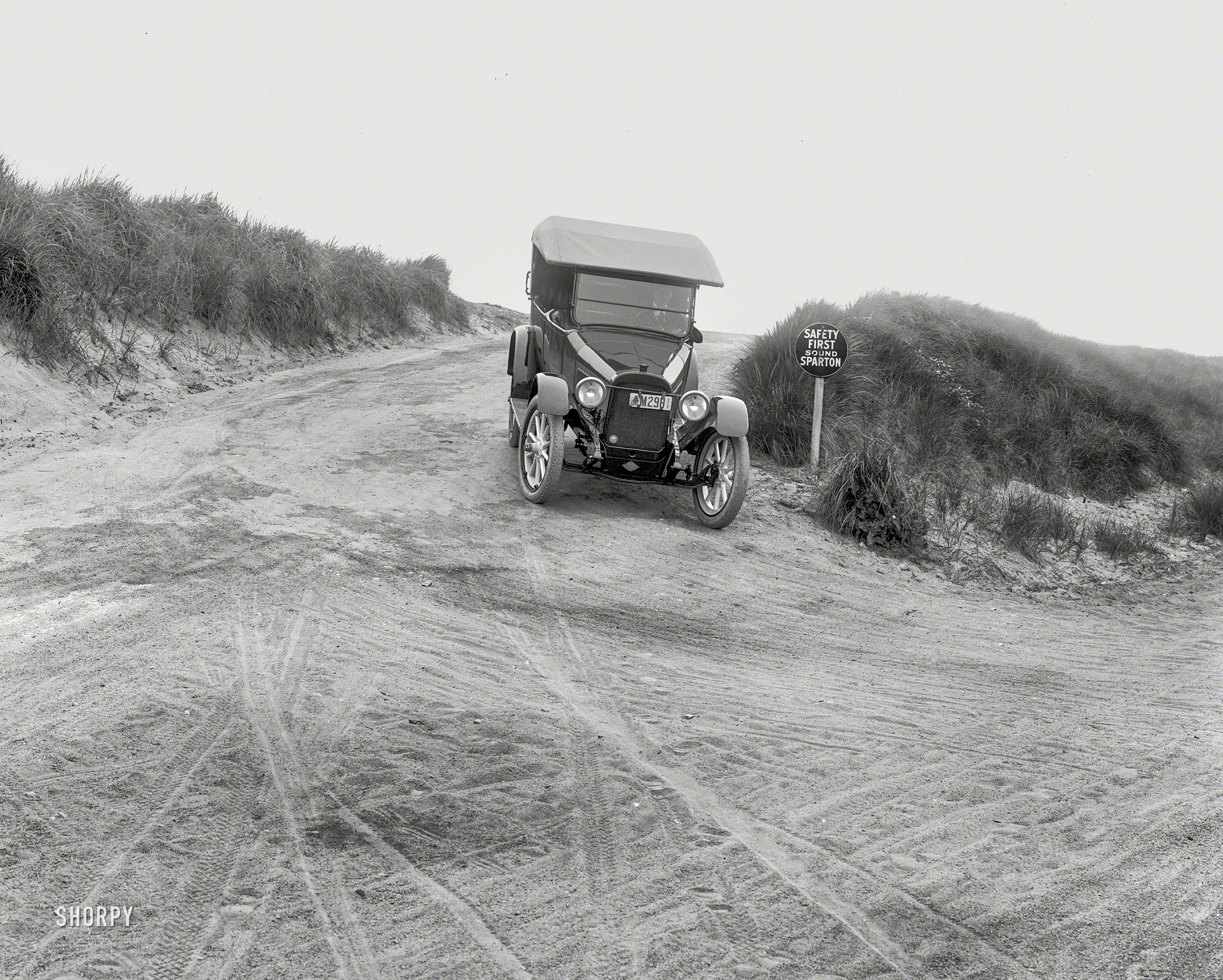 California in 1918. "Chalmers touring car on dunes." Along with a reminder from the Sparton auto-accessories company to sound your horn -- branding disguised as a safety message. 5x7 glass negative by Christopher Helin. View full size.