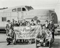 Oct. 8, 1936. "H.O. Harrison Pontiac -- 'crack salesmen' and wives 'Going East' on streamliner City of San Francisco." 8x10 acetate negative. View full size.
Not just the salesmen and wivesSomeone's daughter is there - notice the sailor suit and the bobby socks and saddle shoes of the young lady in the middle.  I can't figure out who she's related to - possibly the woman with the gloves on the left hand side of the sign.
Watermarks, againDave:  I just started noticing the Large watermarks, and I've been a Shorpy reader since 2007.  You have to do what you have to do.  I've always assumed that if I bought a print, it would be removed, yes?
[Watermarks are not on Shorpy's prints. -tterrace]
Now I'm wondering if you're the same Dave from Plan 59, previously Ephemera Now, where I have purchased several "Meat" prints.
[Yes. -tterrace]
Bless you and the work you do, it always brightens my day.
Don&#039;t Mind the Watermarks        I'm an enthusiastic fan of photogrpahy and have often complained about obnoxious watermarks. They never bothered me on Shorpy. They are small, always placed so that they don't obstruct any detail and generally blend into the black &amp; white photos well.
Dave's comments regarding pirated photos endangerng the future of Shorpy are a little alarming. I visit this site every day and really enjoy it. I'm going to make a point of finally ordering a big print of that Rock Center photo in the next month or so.
Watermarks ReduxConsidering that Shorpy and his staff put in a load of time and effort, and provide us with these great pix at NO COST, there should no nit-picking because the site wishes to protect their work product.  There is at least one historical photo site I visit regularly that uses a watermark that occupies 25% to 30% or more of the image.  Of course, I will not name them here, as they are simply exercising their right to protect their property.  They market those images, much as Shorpy does.
Star ChieftainsLove this streamlined-'30s image!  If these fellows had stuck with Pontiac for another 20 years or so, then they could have been billed as "Wide-Track Salesmen."  In the meantime, I'm casting a 1937 Hollywood version of this journey, in which the two jaunty-hatted women on the right end of the line would be played by Myrna Loy and Helen Broderick, respectively.    
Shorpy WatermarksI love the ingenuity of the watermarks. They sometimes blend in so well, I gotta take extra time to find them. Hats off to you, Dave! Shorpy takes me to places that resemble the photos in the old shoe box at home, when I was a kid. Kudos!
Union PacificThat's a Union Pacific M-10003 or 4, which my father had in a Lionel version, made of heavy cast metal, but which was quick to derail.  The larger Lionel M-10000 that he had, which negotiated only double-radius O-72 curves, was much more stable.  Apparently the M-1000 was the earlier version historically but probably later in Lionel production.
Grinning GrillesThis early diesel-electric locomotive was semi-permanently coupled to its special train set. I am told the crews did not appreciate the gaping air intakes when, for example, the locomotive encountered an unfortunate skunk on the tracks. Operated by Chicago &amp; Northwestern, Union Pacific, and Southern Pacific, the passenger demands soon outgrew its limited capacity for travel between Chicago and Oakland. It was soon replaced by a much larger train which was wrecked by sabotage west of Carlin NV in 1939.  
39¾ Hours to Chicago!Southern Pacific poster. This was actually taken in Oakland, which was as far as the train could go. San Francisco passengers were ferried across the Bay.
SurvivorThe Great Depression was particularly hard on auto dealers, whose revenue depended on people with disposable income.  Henry O. ("H.O.") Harrison had built a minor empire of car and truck dealerships around the Bay Area (while ranching and dealing in commercial real estate elsewhere in California). He and his principal business (H.O.Harrison Company) filed for bankruptcy at the Depression's peak, but as this photo reflects, he was soon back on his feet. By the time of the 1940 census, he and his wife Daisy and daughter Margaret were living in an apartment on Washington Street in San Francisco, right on a cable car line.   
WatermarksI agree with valueseekinguy that the watermarks detract a bit. I like to show off Shorpy pics as wallpaper on my work machine. I just try to choose ones where the watermark isn't as noticeable.
I also understand where Dave is coming from. Restoring old pics can take a great deal of time and work.
If it helps to keep Shorpy going, I don't mind the very minor inconvenience.
UglyThat has to be the ugliest locomotive I've ever seen. How that ever got through the design stage I'll never understand. I wonder what else the designer came up with if that was his best.
WatermarkedAll-in-all, that's a pretty tame watermark. Well worth the ability to get to view these images in hi-res. Hope this site never goes away.
Call Me BlindBut I can't even see it, the watermark that is, not the train
Fabulous shape!I like all the women in this salesMEN shot.
But even more the streamliner. - more shots of that amazing body please!

My, how times change."Crack Salesmen"?
Appreciation I rarely comment here, but I visit this site every single day.
It is one of the best, and all the Curmudgeon Crew can contribute is harping about "watermarks"... seriously??
It takes true dedication and surprisingly hard work to maintain fresh content 7 days a week, every week.
Keep it up Shorpy crew, I and others truly appreciate the daily "trips" down memory lane !!
Not Impressed With The Watermark On The LocomotiveI notice lately you've been adding a "Shorpy" watermark through the middle of your pictures. I think it drastically detracts from what you are doing. As a hobby, I used to color some of the pictures for my own use but now I have extra work to remove the watermark.
[Tell that to the dozens of people who rip off our images to sell as prints on eBay. Much more of that, and there won't be a Shorpy. - Dave]
WatermarkedThat is the curse of digitalization. Copying will not degrade the object being copied. 
The second curse is that too many people think everything in the WWW is free. Hey, read the terms of use, will ya'! 
On the other extreme, some providers (not Shory.com, mind) think they can charge even more for digital products, although the overall costs are only a fraction of the respective pre-internet hardware product, what with tooling, stocking, transport, wholesale, retail and sell-through risk, which all are nonexistent in digital distribution. 14 bucks for the CD, OK. But 13 bucks for the same in digital? C'mon!
Fabulous ladies&#039; hats!If I'm ever transported to the past, I will definitely try to find work as a milliner.  These hats are the peak of prewar whimsy; they are so optimistic and jaunty.  The salesmen and their wives are so happy to have earned this terrific trip--Where are they going?
Progress?It's quaint that that locomotive could propel you from Chicago to Oakland in 39 and 3/4 hours.  Of course today, with all our modern wizardry, you can make the same train trip in a little over 52 hours.
GorgeousThat is  the most Beautiful train I  have     ever  seen!
(The Gallery, Cars, Trucks, Buses, Railroads, San Francisco)