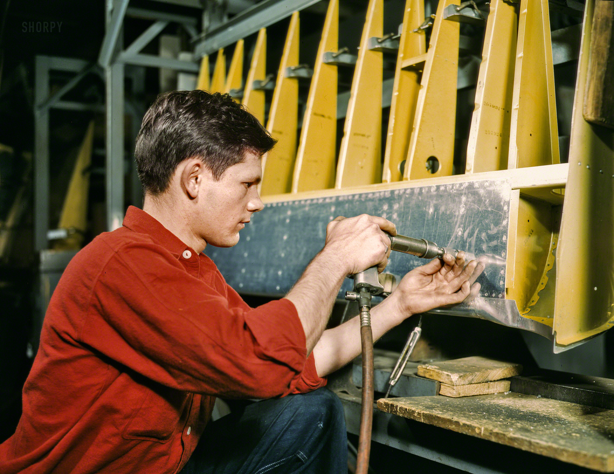 October 1942. "Riveter at work at the Douglas Aircraft plant in Long Beach, California." Kodachrome transparency by Alfred Palmer. View full size.