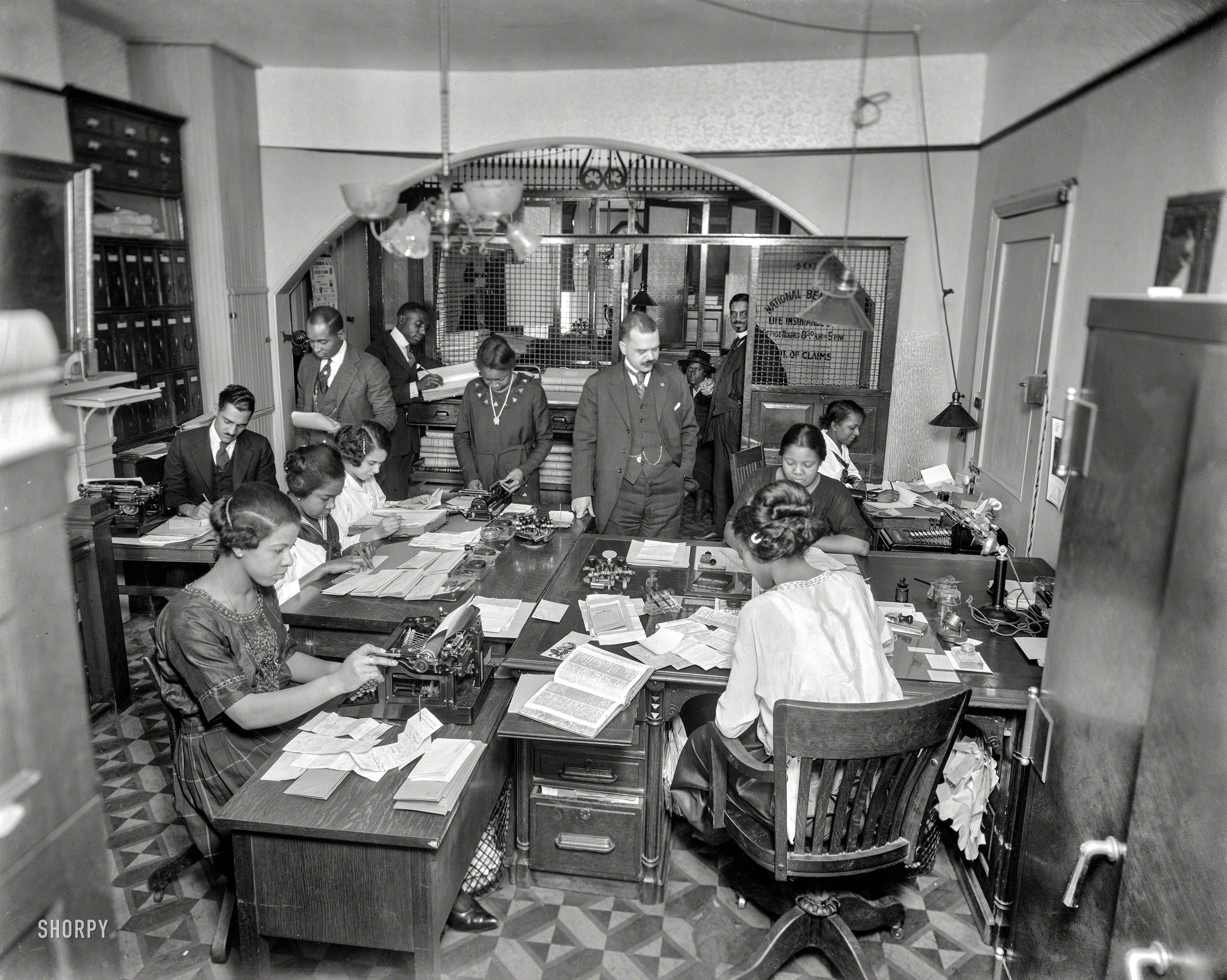 Washington, D.C, circa 1921. "National Benefit Life Insurance, interior." Described in contemporary accounts as the nation's largest "colored insurance company." Harris & Ewing Collection glass negative, retouched to obscure whatever is on the wall behind that lamp in the corner. View full size.
