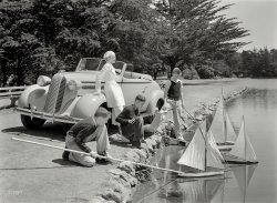 April 8, 1936. "Pontiac convertible at Spreckels Lake, Golden Gate Park, San Francisco." A model family's model boats. 8x10 acetate negative. View full size.
What a streamlined beauty!The Pontiac's nice, too!
BA-BOOM!
That NEVER gets old!
["At her best with the top down." Watch and learn, lads. - Dave]
7-Foot VoyageWhat did they do when the sailboats drifted beyond the reach of the bamboo? Nobody in this photo seems dressed for aquatic retrieval of wayward vessels. 
Boat chasersThe lake is only 950 x 420 feet so they probably just ran around to the other side to get their wayward boats. Or maybe that nice lady will give them a ride. It is still home of the San Francisco Model Yacht Club.
Dress CodeHer ensemble seems better suited to leaning against a Cadillac ... or a LaSalle, anyway.
Contrasting contemporariesI doubt that Steinbeck was spending much time hanging out with these folks.
Two-seater?It must have been crowded when all four of them rode to the lake in that 2-seater cabriolet.
[This four-passenger Pontiac DeLuxe Cabriolet has a rumble seat. -Dave]
Weather GaugeLooks like the closest boat has what little wind there is (he's got the weather gauge) which means the others are trying to sail with nearly zip wind.  In any case it doesn't look like there is much wind anyway.
(The Gallery, Boats & Bridges, Cars, Trucks, Buses, San Francisco)