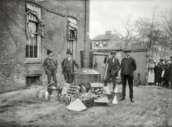 November 11, 1922. Washington, D.C. "Still." Back-alley Mason jar hooch in the early years of Prohibition. National Photo glass negative. View full size.
Nice haulI like to imagine the grinning lady by the fence thinking, "Okay good, they only found the decoy still and the small stash, so let's let them be proud of themselves."
Reminds me of the series &quot;Boardwalk Empire&quot;and the futility of "Prohibition" of anything.
No, not the jars!I hope if they were going to get rid of that hooch they didn't break those beautiful canning jars, like I've seen in films from that era! I've saved many a home grown vegetable and bulk picked or purchased fruit in jars like that. Those half gallons are especially hard to find! 
(The Gallery, D.C., Natl Photo)