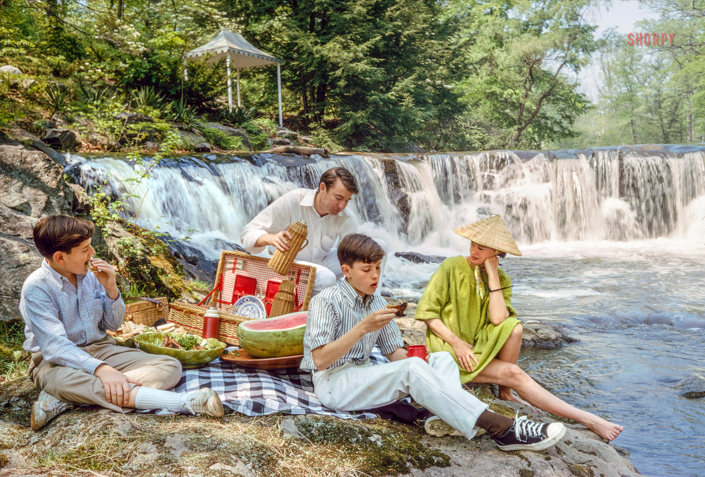 May 1964. 35mm Kodachrome by Toni Frissell for the Life magazine assignment "The Splendor of a Great Family: The Vanderbilts." View full size.
&nbsp; &nbsp; &nbsp; &nbsp; On her country estate near Stamford, Connecticut, Gloria Vanderbilt enjoys a picnic with her husband, Wyatt Cooper, and two sons by her marriage to Leopold Stokowski -- Chris, 12, and Stan, 13. She came upon the picturesque waterfall with its secluded cottage one day and couldn't resist buying it. "It was like something out of a fairy tale," she exclaims.