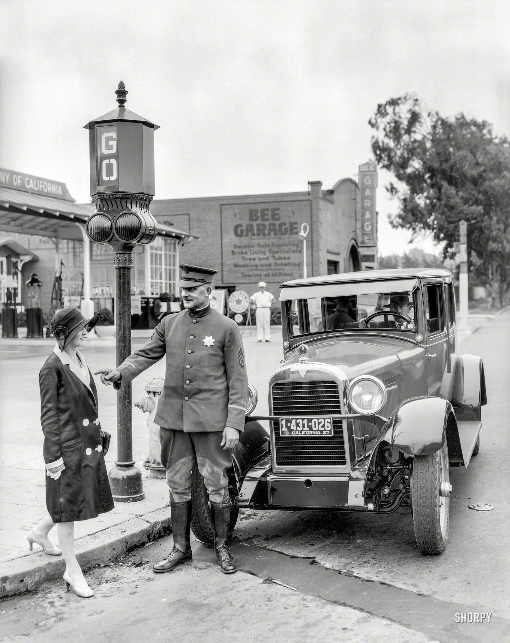 San Francisco, 1927. "Traffic signals -- police officer stops pedestrian crossing against the light in front of Hudson sedan at Bee Garage service station." 8x10 film negative, originally from the Wyland Stanley collection. View full size.