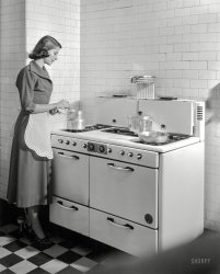 New York circa 1948. "Homemaker stirring double boiler on gas range." The lady with the tiled kitchen last glimpsed here. Photo by John M. Fox. View full size.