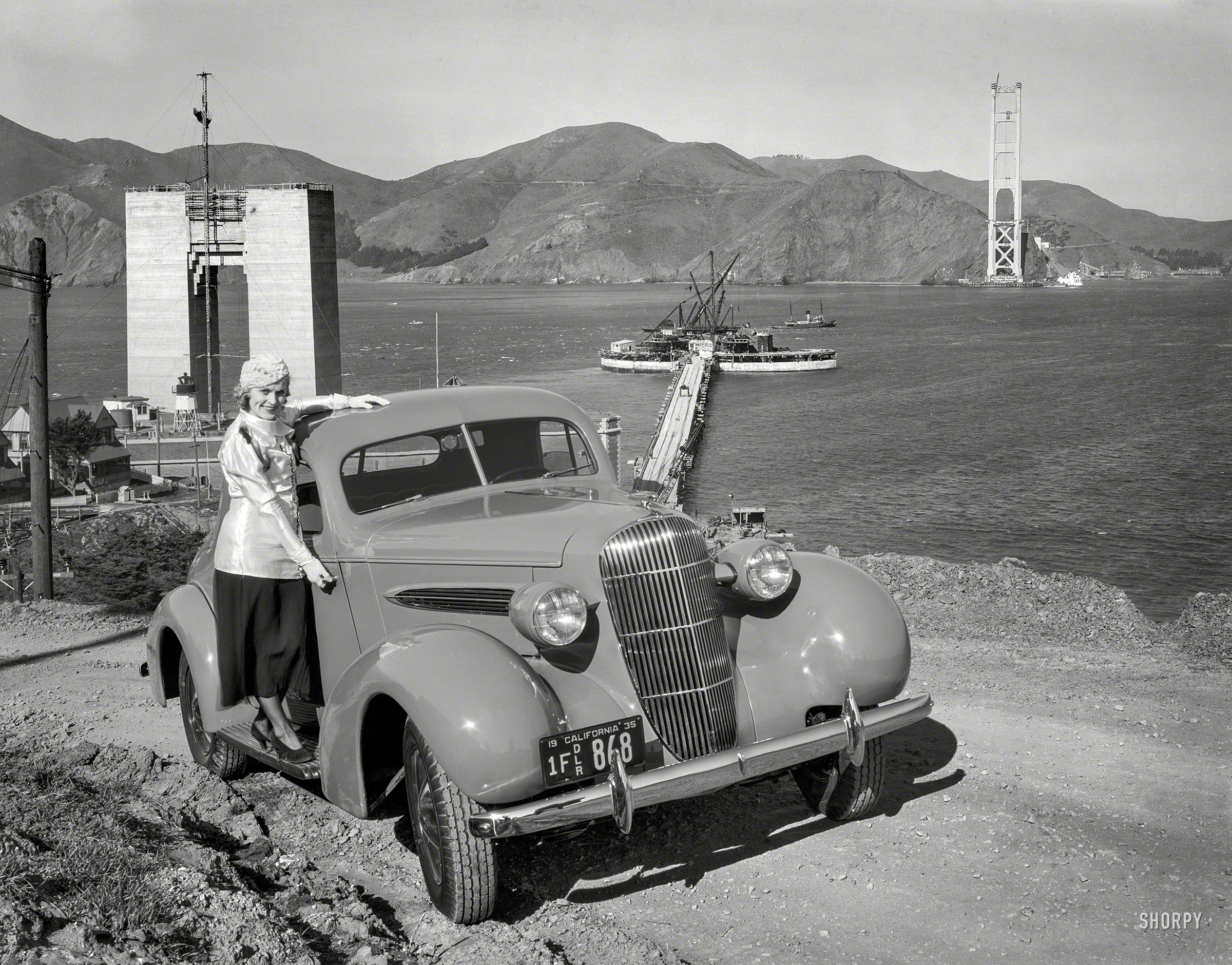 San Francisco, 1935. "Oldsmobile coupe and Golden Gate Bridge under construction." Only two more years and this lady will be able to cross. 8x10 film negative, originally from the Wyland Stanley collection. View full size.