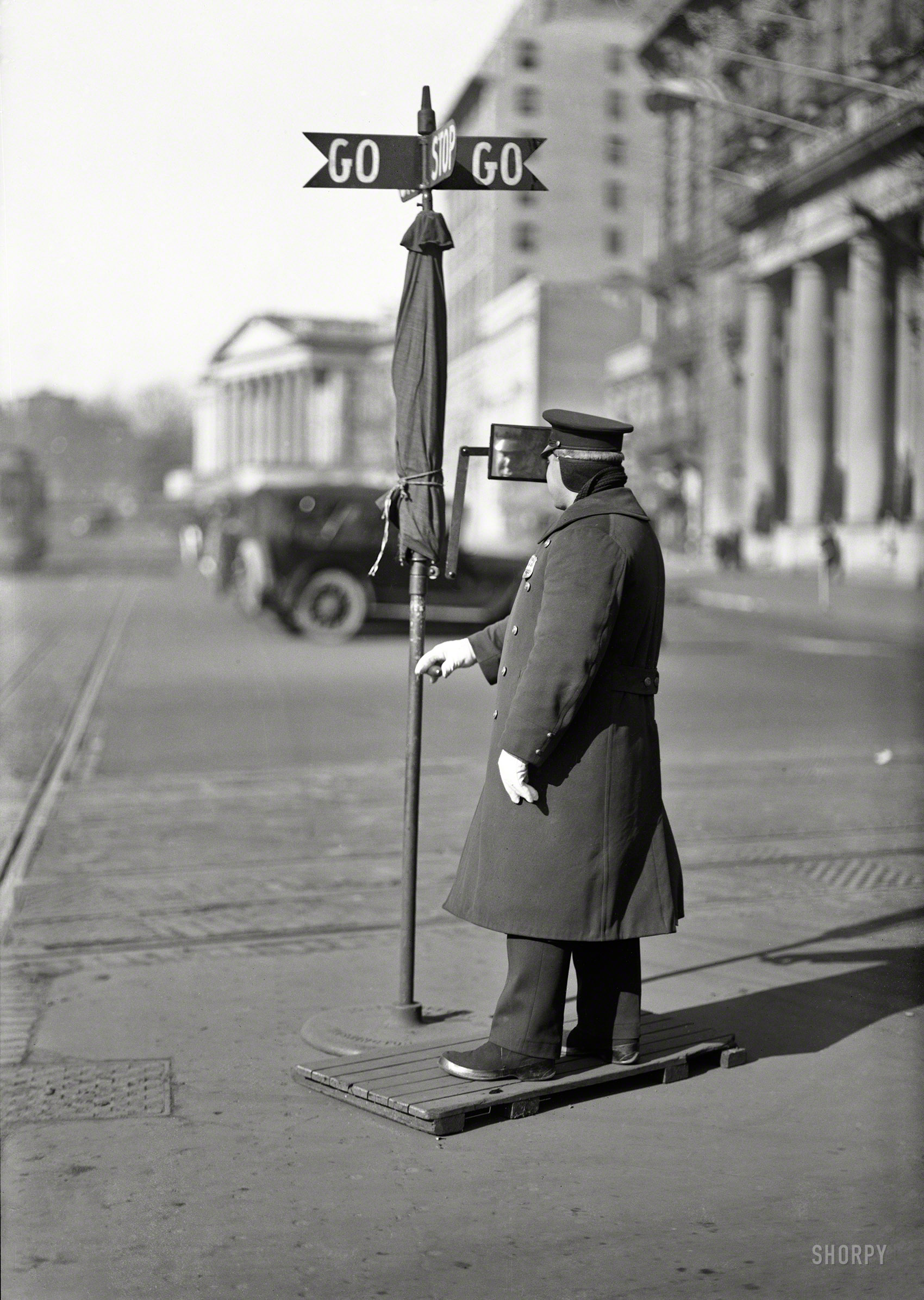 Circa 1919. "Traffic officer at 14th Street and Pennsylvania Avenue." Before stoplights in the District of Columbia, there was the "Go-Go" traffic sign equipped with umbrella and rearview mirror. The Willard Hotel and U.S. Treasury play supporting roles in this Harris & Ewing glass negative. View full size.