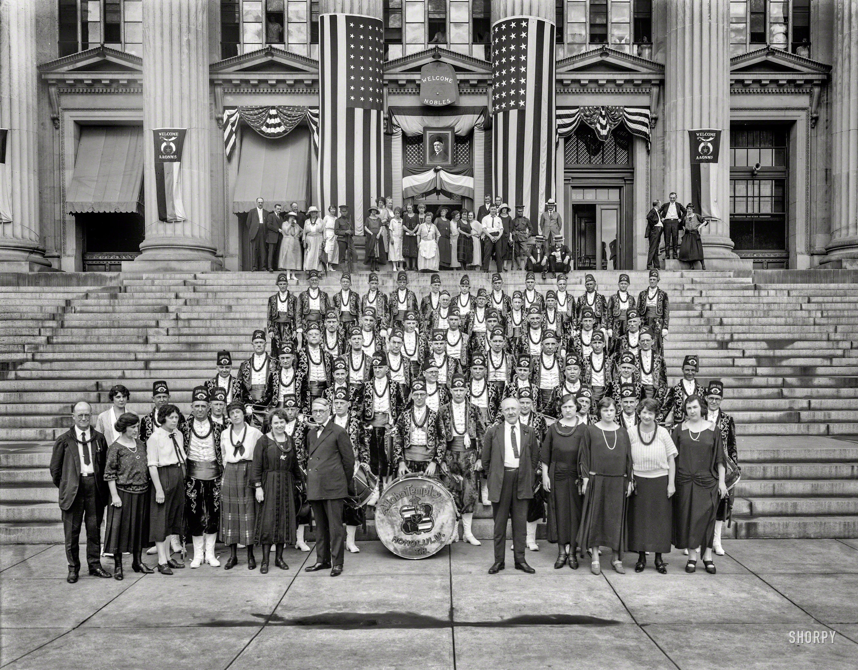June 1923. Washington, D.C. "Aloha Band at Bureau of Engraving and Printing." Welcoming the Ancient Arabic Order of the Nobles of the Mystic Shrine (AAONMS) during the Shriners convention, with a portrait of President Warren Harding, noted Mason (who would be dead by August), over the entrance. National Photo Company Collection glass negative. View full size.