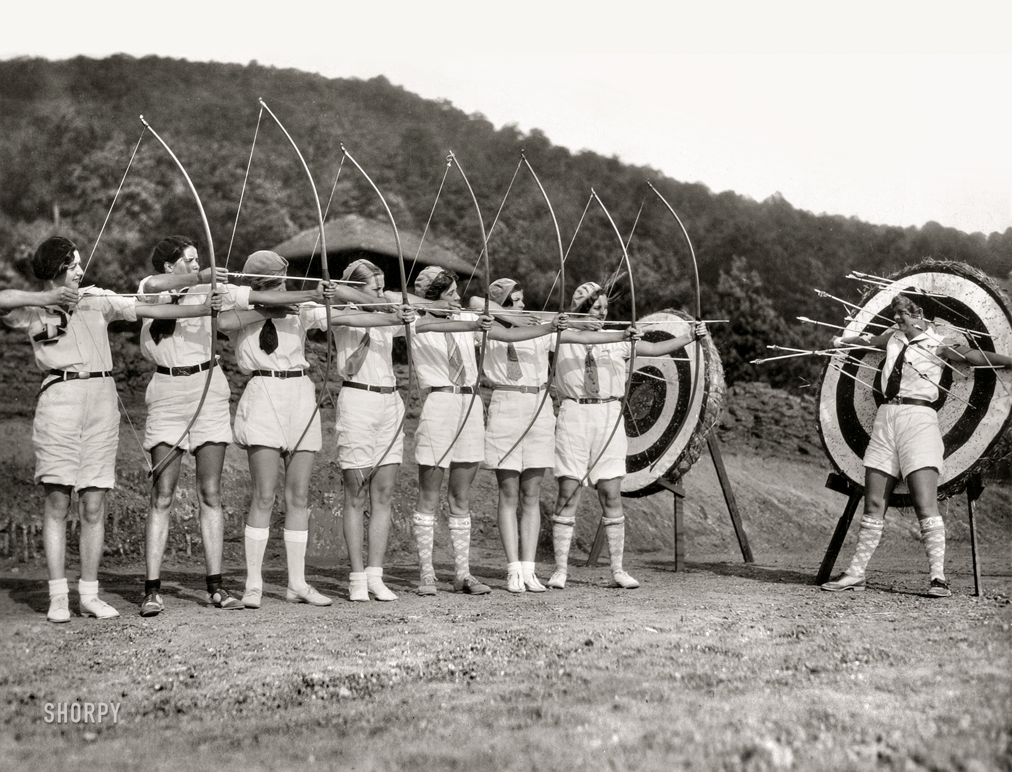 &nbsp; &nbsp; &nbsp; &nbsp; "Girl archers from Camp Greystone, Tuxedo, N.C., demonstrate fancy shooting attired in latest fashion for the bow and arrow sport -- 'shorts' and sox."
August 23, 1928. "A perfect miss with every shot -- Miss Isabel Bonsack of St. Louis, Mo., has a right to feel happy that her fellow members of the Camp Greystone archery team are skillful markswomen. Miss Bonsack volunteered to act as a target during an exhibition of girl archers at the Grove Park Inn, Asheville, North Carolina." Gelatin silver print. View full size.