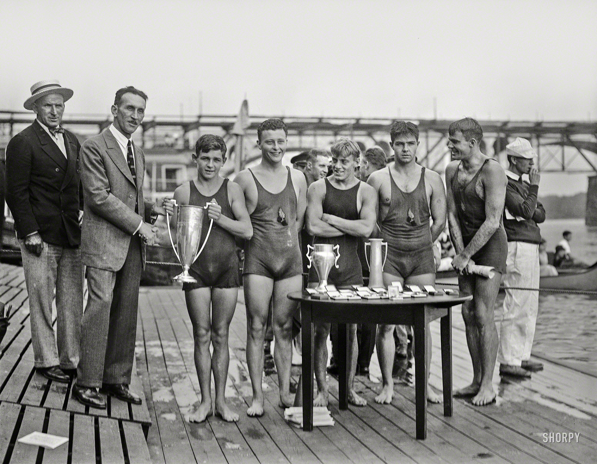 August 27, 1927. "Raymond Ruddy, 15-year-old New York Athletic Club swimmer who won the race on the Potomac, with members of the victorious team -- Lee, Fissler, Farley and Geibel -- on Washington Canoe Club float at Chain Bridge." Harris & Ewing Collection glass negative. View full size.


NEW YORK BOY, 15, IS WINNER
OF THREE-MILE SWIM ON POTOMAC
Raymond Ruddy First in Test for President's Cup
&nbsp; &nbsp; &nbsp; "His tapering legs and well-formed body apparently visualized the Greek athlete to all, as this comparison was general as he stood on the Washington Canoe Club float at the finish."
-- Washington Post


RAY RUDDY, OLYMPIC SWIM STAR, KILLED
BY PLUNGE DOWN FLIGHT OF STAIRS

&nbsp; &nbsp; &nbsp; Raymond Ruddy, whose achievements as a swimmer and water-poloist caused him to be ranked among the outstanding athletes of the world, died at 7 o'clock last night at the age of 27 in Columbia Presbyterian Medical Center from the effects of a fall twenty-four hours earlier.
&nbsp; &nbsp; &nbsp; The swimmer was about to leave the home of his aunt when his foot caught in the carpet of a stairway leading down from the second floor. He lost his balance and fell nearly the entire flight, striking his head against a radiator on the first floor.
-- New York Times, Dec. 5, 1938
