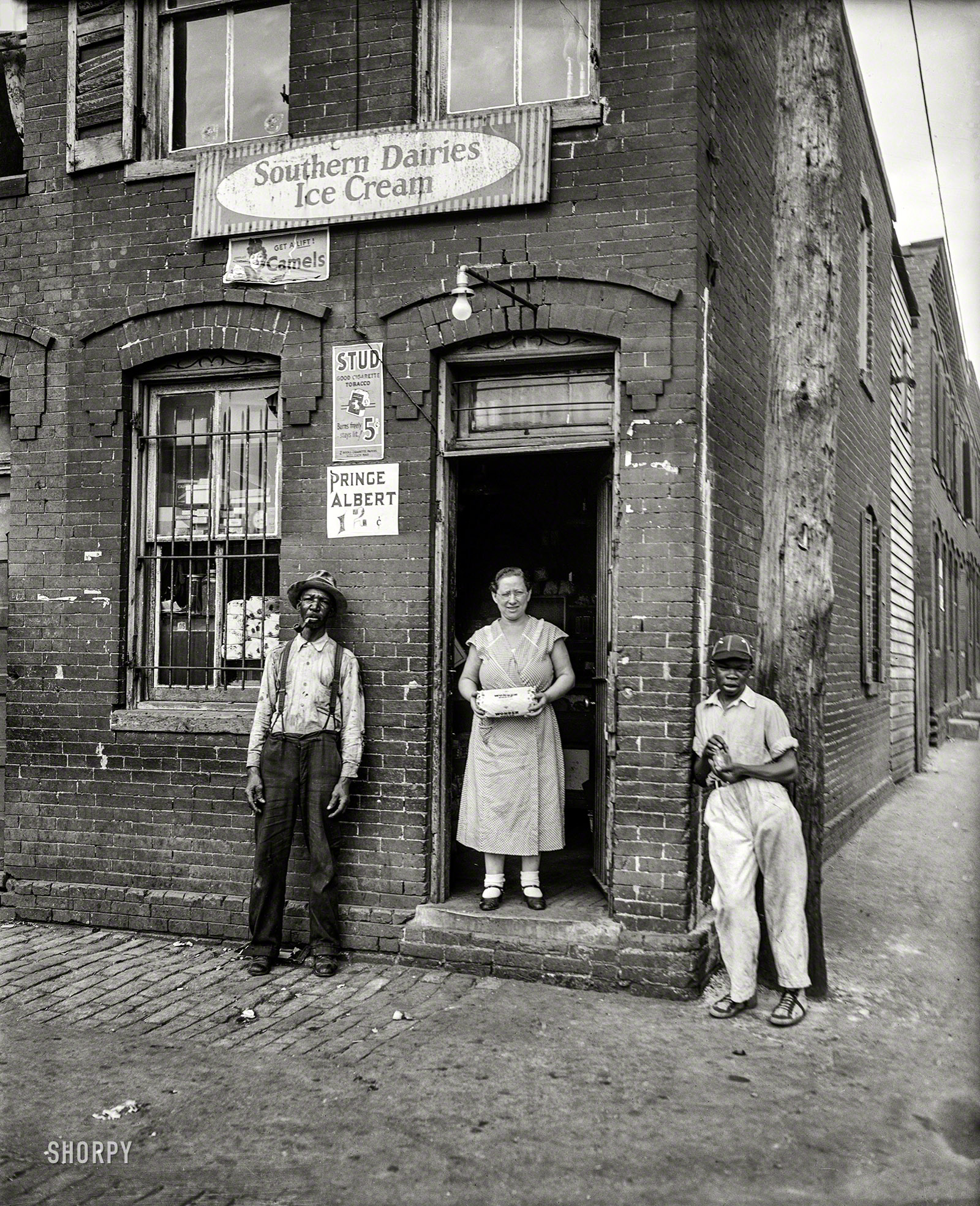 Nov. 28, 1935. "Washington, D.C., street scene." One-stop shopping for Wonder Bread, Stud, Prince Albert, ice cream and what-have-you. View full size.