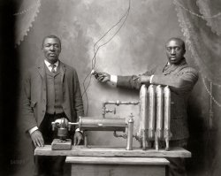 "Start of super heating union. [Inventor Charles S.L. Baker and another man, possibly his brother Peter, standing behind heating (radiator) system.]" Photo by Bode, Fifth and Felix Streets, St. Joseph, Missouri. Copyright by Charles S.L. Baker, Feb. 12, 1906. View full size.
The Original Friction HeaterCharles Baker invented the Friction Heater, which is shown in this photo. It consisted of a motor (left) that turned a shaft inside a water jacket that rotated a revolving wooden core that rubbed against the inner metal cylinder of the water jacket creating friction heat. The fluid in the water jacket heated up, flowing through the radiator (right) thus warming the space it was set up in. He got the idea originally when he was too lazy to grease the hubs of his father's wagon and the resulting heat failure of the wheels.
An article about this invention appeared in the Michigan Manufacturer &amp; Financial Record, Volume 7, No. 7, August 12, 1911.
https://books.google.com/books?id=x7HmAAAAMAAJ&amp;pg=PA16-IA17&amp;dq=%22charle...
Nifty, but scaryThe man on the right is working the switch to the motor, which is on the left, which drives a cylinder inside a cylinder for a friction heater--that's the long cylinder on its side in the middle.  You could power it with an electric motor (this case) or any other source (gasoline motor, etc..) of mechanical energy.  You could call it an electric heater that didn't need nichrome (or other resistive materials) or lossy induction to work.  One writeup I saw from "The Michigan Manufacturer" suggests Baker came up with the idea after neglecting to grease pins and axles on a wagon.
Nifty, but a bit of Rube Goldberg here if it's powered by a gasoline engine.  I would also guess, as anyone who's ever worked on brakes would guess, that wear and noise were likely issues that users/owners had to deal with.
Scary; the way it's wired.  The man on the right is lucky he's not about to be electrocuted, as he's holding a switch for 110V AC with no grounded shield.
(Technology, The Gallery)