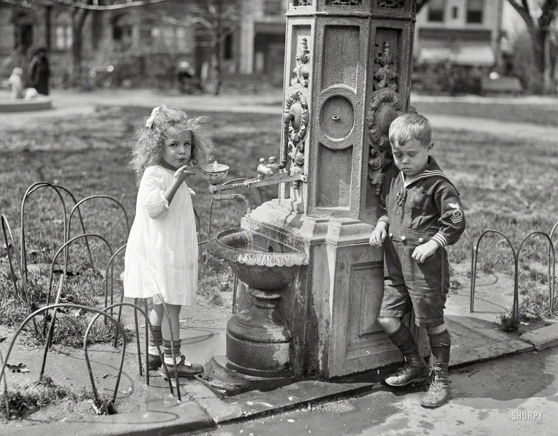 Washington, D.C., 1922. "Children at water fountain." Make mine a double, and get the little lady a drink. Harris &amp; Ewing glass negative. View full size.

