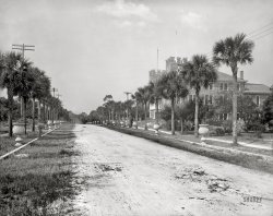 Volusia County, Florida, circa 1906. "Palm avenue, Seabreeze." At right is Wilman's Opera House, with a sign advertising the real estate business of opera house manager Charles Burgman. 8x10 inch dry plate glass negative, Detroit Publishing Company. View full size.
Two highest points in FloridaThe street eclipsed only by the sand dune on the right. 
May you never run out punsNot there is any sign of it.  
Planters?Okay, I’ll bite: what was the actual purpose of these urns?  To be public planters?  I wonder who would tend them.  Nowadays they’d be filled with empty cigarette packs and butts.
Streets of Confusion"Seabreeze" was both the name of major street in Daytona Beach, and a separate town to the north, whose main street was named Ocean Boulevard  (I think that's what we're seeing here, looking west). The two towns later merged, and Ocean Boulevard was renamed Seabreeze Boulevard, while Seabreeze Avenue seems to have been renamed Main Street. Questions?

A similar shot from further east on the grounds of the Clarendon Hotel - the town seemed to have something of a battlement fetish! - with the building three long blocks distant. 


The two Wilmans' buildings that straddled Pine Grove Avenue
Florida real estate boom in the makingAn elegantly accoutered but unpaved, partially-overgrown "avenue" with elegant building on one side and (possibly) nothing on the other: welcome to the fantasyland of Florida real estate, then and now.
[Indeed. The partly obscured sign at the entrance reads "[Burg]man and ***sden Real Estate." - Dave]
The best known Florida real-estate bubbles were in 1926 (see the Marx Brothers' 'Cocoanuts') and 2008 (see 'The Big Short'). Seabreeze--now a historic district of Daytona Beach--probably had the lucky timing to escape. 
I have seen later postcards where a similar wide be-urned street was labeled "Ocean Boulevard" or "Seabreeze Boulevard."
Urn AvenueJust, WHY?
Well urned, not well postedWhy?  They are for leaning your bicycle against, as somebody did with the fourth urn back on the right.  But what's that unusual short post with the hole in it near its top by the second urn on the left used for?
[Parking your horse. - Dave]
(The Gallery, DPC, Florida)
