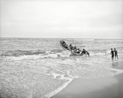 Asbury Park, New Jersey, circa 1903. "Landing through the surf." 8x10 inch dry plate glass negative, Detroit Publishing Company. View full size.
Bowline, methinksWhy is everyone so sure there's no bowline in this picture. It's hard to see, but there seems to be some sort of straight white line near the bow of the boat.
[This is one of a series of photos showing both launching for and landing from an excursion on a fishing schooner off Asbury Park. Below: A "launch" photo with a different group of people. - Dave]
Accident-free fun!Nothing could go wrong here, could it?  Also love the boys -- excitedly at the edge of grown-up shenanigans.
Odd Way to LandLooks more like a launch to me.
Looks more like Launching thru the surf.
ReversoThey're not landing the skiff, but rather launching it. The men at the stern are pushing it. Also, you would normally land bow first, especially in heavy surf. The wave action would assist in the landing. With the bow seawards, it cuts the wave and actually wakes it more difficult to land.
["Landing through the surf" (the title of the etching below) is often done with the boat turned seaward.  - Dave]
&nbsp; &nbsp; &nbsp; &nbsp; An officer in the US Coast Guard, who has much experience in landing through the surf, gives the following method as the safest and best for landing through the surf with a crew inexperienced in surf work -- place a 40 to 60 pound anchor in the bow with 100 to 150 fathoms of line. Just before getting into surf turn your boat to seaward, drop your anchor, pay out on line and one will usually find that the surge of the sea will take her to the beach fast enough, and if not, use your oars to back-in. Be careful to keep strain on line so that the boat will always be kept head-on to seas.
-- From the 1930 edition of "Modern Seamanship" by Rear Admiral Austin Knight, USN.
Famous last wordsThe man said he's not taking us out far enough to need life jackets.
arr, tis a launchHaving significant experience with both seafaring and talking like a pirate, I wish to weigh in on this one.  It is almost certainly a launch pictured here, not a landing.  The method described below by Admiral Austin Knight will work only if an anchor line is used from the bow, which is clearly absent in this photo.  Without the line to keep the bow seaward, once the stern beaches the next wave will sweep the bow to the side, capsizing the boat and emptying its contents into the surf.  In fact, the same can even happen with a poorly executed bow-first landing.  I know because I have done it.  Arrr.
Re: ReversoHowever, no such anchor line is in evidence. The simpler explanation is that whoever wrote the title was wrong.
Curiouser and CuriouserFirst, they are not using the method described by Admiral Knight because there's no sign of an anchor line. Second, the engraving of the stern-first method shows the condition of its use, which is surf heavy enough to provide a grave risk of having a wave break over the square stern. That is not the case here. Finally, if the two gents were really assisting in a landing, they are standing in front of a heavily laden boat that is coming at them at the speed of the surf, holding their arms straight. That is a good way to get run over and injured. In a proper landing they would be on either side, assisting the boat onto the beach. All that, plus the way the passengers are sitting and looking forward, reinforces the likelihood that this is a launch through light surf.
(The Gallery, Boats & Bridges, DPC)