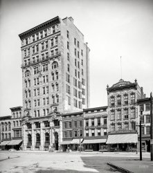 Utica, N.Y., circa 1905. "Utica City National Bank, Genesee Street." Partners in commerce with various purveyors of hats, caps and "mattings." View full size.