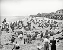 The Jersey shore circa 1905. "On the beach at Ross' pavilion, Ocean Grove, N.J." Short of tuxes and ballgowns, it's hard to imagine being any more dressed up at the beach. (And cheer up, guy in the middle -- your problems are over by now.) 8x10 inch dry plate glass negative, Detroit Publishing Company. View full size.
Just CuriousDoes anybody know what the ropes are for?
[You grab onto them so you don't drown. - Dave]
yeah, i get that - but, in the sand? ...or does high tide bring the water up that far?
Casual workerTalk about laid back.
A perfect setting for the old Rodney Dangerfield jokein which a small boy runs up to a cop, pleading, "Officer, I'm lost! Can you help me find my parents?"
"Gee, I dunno, kid. There's so many places they could hide."
Anyone notice this?Looking at all the people on this beach you see them with nary anything around them on the sand. Mostly just themselves. Maybe a newspaper or two.
No towels, blankets, ginormous coolers filled with sodas, beer, or food, no boom boxes, no games, no toys, tote bags, floating toys, etc. So simple.
Beach was a breeze to clean up in the morning I bet.
Taking the sea airIn the days before modern drug treatments, the sea air was considered highly therapeutic. People with consumption (TB) for example, as well as other diseases were thought to benefit by breathing the salt-laden air. Hence the folks on the pier, and even inside the wide-open windows, are breathing in the therapeutic seaside breezes.
Insouciantyet alert, lifeguards still adopt that same pose a century later.
Blue LawsDo we think their beachwear was restrictive? The town was developed by the Camp Meeting Association, a Methodist group from Philadelphia. Before a 1981 court decision, they allowed no automobiles to be driven in the village on Sundays.
Ouch!That man in the suit and white hat is gonna need a chiropractor with that large rope tied around his waist!
It seems in 1905that people truly had no idea of the purpose of a beach, complete wool suits for men, 12 yards of material in dresses for women and crocheted tablecloths for shawls, some wearing what looks like bathing suits, others fully dressed plunked on the sand, and beyond, hundreds of fully clothed gawkers lining the shore, there seems no purpose to any of these shenanigans.
It&#039;s no useI find neither Zelig nor Waldo here.
OverdressedOr not, (almost) everybody seems to be having a good time.  Why else would they be there?
Well, I never!One of them fancy photographer fellers with his no-good box.
Original Bumbo SeatNo one seems to have noticed the little tyke with the Buster Brown haircut in the lower left corner of the photo in front of the two women with shawls.  The sand has been molded into a seat obviously by an adult to keep the child put.  Ingenious.  
Re: &quot;Well, I never&quot; ladyLooks like she's wearing her "Marcel" original Chapeau   
The Scarlet LetterI know what an "A" stands for, after all we were forced to read the story in high school in the 60's, but what does the "R" stand for on the dude's chest?
[Perhaps the caption contains a clue. - Dave]
WarmI figure, after a winter with no central heating and coal smoke permeating the city, sitting at the beach in the fresh air and warmth felt pretty good, even in your wool suit.
The &quot;guy in the middle&quot;Do you think he's sad because he forgot his bathing suit?
(The Gallery, DPC, Swimming)