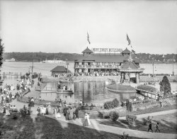 1906. "Kingston Point Park, Kingston, New York." A grand day out on the Hudson River. 8x10 inch glass negative, Detroit Publishing Company. View full size.
There&#039;s not much of it left nowThis Google Earth satellite view shows the same area in September 2013.  The island near the center is where the bandstand stood.  The 1906 photo is looking generally east, which is at the top of the satellite view.
Central-Hudson Steamboat CompanyThe side-wheeler in the background has the name Central-Hudson on her paddle box. This is the Central-Hudson Steamboat Company of Newburgh, NY. I cannot make out the vessel's name, but she has many interesting features including boilers and short smokestacks placed on sponsons (overhangs) on each side. There's a clerestory over the engine room amidships. Placing the boilers away from the centerline was considered to be a precaution against boiler explosions.
Can anyone make out the name of the ship?
There's a freight train on the far shore. There are still active tracks there today.
In the foreground pond r.l. we find a handsome pulling boat with a wineglass transom, possibly a "Whitehall boat". The boat with the flags seems to be a power launch. Best of all is the canoe-sterned launch at anchor.
Now, somebody please explain the crossed whatever-they-are at the base of the spire on the gazebo !
Same spot...and same time...just minus the people.
Trolley dikeThe larger structure appears to be a terminal at the end of a long dike that still contains trolley tracks.  Back in town just beyond the base of the dike lies the New York Trolley Museum.  Hopefully they have a poster of this image on display there.
An intermodal facilityThe railroad tracks clearly visible in the satellite photo Larc posted got me interested.  Apparently the big structure under the sign is both a railroad station and a dock; passengers on boats from New York City or Albany could transfer to the Ulster and Delaware Railroad there, and vice versa.  The railroad would take them to hotels in the Catskill Mountains.
Today, the Trolley Museum of New York operates trolley cars along the railroad line, from this location to about a mile south.
Name of the boat.It seems that the name is Central-Hudson. You can see it clearly 
here, on the paddle box and bow plate. Maybe it was the flagship of the line.
Victorian Age in All Its GloryThis is what I think of when I think of the Victorian age.  Fancy dresses, suits, hats, and gazebos.  They don't make parks like this any more, strictly for their beauty and relaxation. What I wouldn't give to jump in a DeLorean and travel back to this era. 
It's a joyous scene.  You could take a boat out for a row, have a bite to eat along the wharf, or simply sit by your honey and woo her.
Great picture!
(The Gallery, Boats & Bridges, DPC)