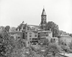 &nbsp; &nbsp; &nbsp; &nbsp; 2:08 p.m. on a washday in Marblehead, Mass., 110 years ago.
1906. "Abbot Hall, Marblehead, Massachusetts." The town's Romanesque city hall and clock tower, completed in 1876, and surrounding residences. 8x10 inch dry plate glass negative, Detroit Publishing Company. View full size.
Dark interior?The building - far right - has two floors of opaque shutters. it's about the size of a two or three car modern garage with an upstairs level. Might this have been a carriage house with apartment for the help upstairs - possibly having large windows on upper floor out front - - - 
My home townThis is my home town. Abbott Hall houses original "Spirit of '76" painting. John Glover, founder of the American Navy, and commander of the foul-mouthed sailors and fishermen who saved the ragged Continental Army's ass not once but twice, lived just over the hill. Proud to be from there--as it was.
Still Standing.......and here's a colour postcard of a similar view from the 1920s.
They are still there.It appears every building in this photo is still there.
Buildings are Still There on Washington StreetThe building with the round cupola on the roof is still there at 183 Washington Street; the buildings to the right of it are also still there at 185-187 and 191 Washington Street, Marblehead, MA.
(The Gallery, DPC)