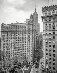 New York circa 1908. "Broadway and Trinity Building." With the Singer tower bringing up the rear. 8x10 glass negative, Detroit Publishing Co. View full size.
What&#039;s going on?Can't figure what's happening.
Are the bride and groom figures dummies, or real people?
There seem to people silhouettes stuck up in the park.
Watching the world go by.I can only spot one person sitting on the sill looking out onto the world.
Cool banners flying the pinnacles of the buildings.
Unfurl That AwningYes, lower that shade.
Just married?Interesting pair sitting on the steps of the big gothic monument in Trinity Churchyard. To my untutored eye, it looks like someone in a dark suit next to someone dressed all in white. Any chance of a closeup?
And can anyone ID the monument? I did a cursory search, but came up with nothing.
[The monument on whose steps this couple are resting is the Martyrs Memorial, aka the Independence Memorial Spire, erected in 1852 to commemorate American patriots who died in British prisons in New York during the Revolutionary War. - Dave]
TombstonesIt appears to be a graveyard around the monument.  Can't figure out the "couple" on the steps though.
[A man in a straw hat and a Yeti. -tterrace]
Too busy to look out the windowThe guy two floors down from the still sitter may have been too busy to watch the world go by, but he made sure he kept a clean collar handy. That one practically glows in the dark.
Trinity and United States Realty Buildings The two gothic skyscrapers pictured are the former Trinity and United States Realty Buildings designed by Francis H. Kimball and constructed between 1904 and 1907.  They both still exist and are Landmarks. 
(The Gallery, DPC, NYC)