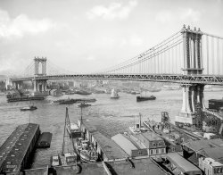 New York circa 1910-12. "Manhattan Bridge and East River from Brooklyn." 8x10 inch dry plate glass negative, Detroit Publishing Company. View full size.
Holiday? Weekend?I was wondering why there are so few people visible? I would have thought it would all be bustling.
[Where would you expect to see them -- rowboats? - Dave]
Fulton FerryThat's the Fulton ferry tucked in behind that Victorian looking ferry building.
Painting DayLooks like a couple of crews are taking advantage of good weather to get some painting done on the cables. I've worked on up high on iron, but I believe I would pass on this.
When sail existed side by side with steamSo much to see and in such detail in this beautifully presented photograph.  Great stuff!
DelightfulIn the enlarged version, that Sailing Schooner about to go under the Bridge.
Met Life TowerIs it possible, from this angle and at this distance, that we see, left of the central dip in the cables, the Metropolitan Life Insurance Company Tower, tallest building in the world from 1909 to 1913, way up at Madison Square Park, on Madison Avenue just above East 23rd Street?
[Met Life is on the left, and there's another on the right. - Dave]
Schooner Barge?An odd craft is on the right, being towed under the bridge. She has two masts forward, apparently rigged with gaff sails like a schooner, but a deckhouse aft more like a "machinery aft" steamship of the period. There's a small funnel, or at least it looks like that in the photo.
Might this be a "Schooner barge?" That's a retired sailing ship with a small schooner rig that can be handled by the crew normally assigned to handle tow and dock lines on a barge. (This would be a very small crew!) The time period is about right. The sailing rig was used to save the tug's fuel, reducing towline force required, in favorable winds, and occasionally tugs would cast off such a barge and let it enter harbor under sail if the wind was strong enough for that and from a suitable direction, saving time for the much more highly valued tug.
The most common trade for schooner barges was coal in bulk. Note there is a coal terminal clearly labeled with a big sign in the photo.
Ferry TerminalI really love the Mansard roof ferry terminal. I know this image is 1912-ish, but when I spotted this building all I could think of was some 1930s potboiler detective film.
Things have changed, littorallyThe wharves in the foreground were replaced by a park and playground in 2002, and are now part of the enormous Brooklyn Bridge Park.

The schooner barge in tow appears to be the Magnolia.
Big AdventureI had the pleasure of climbing to the top of the Manhattan Bridge's Brooklyn tower back in the days before Homeland Security.  Safely accomplished with the help of a series of ladders nested inside of the tower.  The bases of the large globes on the top of the tower were surrounded by large scrunched up and rotting canvas banners protesting the war in Vietnam, which had ended over a decade earlier.
The waterfront activity back in the day of this picture was astonishing, what a rich life, truly metropolitan!  New York's transition to a tourist trap, theme park, shopping mall and mega-rich self-storage depot was just a hundred years ahead.
Re: Met Life TowerCan anyone identify the second tower?  (Mr. Mel, Peter?)
TugYay! More NYC waterfront! I love these pics. That's a Moran tugboat towing the schooner barge. Moran still hale and hearty all these years later. Link to their history at corp website.
DiscoveredThe building on the right is the R.H. Hoe Factory on the Lower East Side.
The boat is a steamer barge, not a schooner barge.  It's not a piteous converted old sailing vessel.  Her sails were for auxiliary use in a very tight margin trade.  
Vantage Point?I'm curious - from which building would this have been taken?  I'd love to see (or take!) a photo from the same vantage point.
(The Gallery, Boats & Bridges, DPC, NYC)
