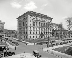 Circa 1916. "Detroit Athletic Club from the Plaza Hotel." Evidently something of a motorcar magnet. 8x10 glass negative, Detroit Publishing Co. View full size.
DAC magazineContributors to the DAC monthly magazine in days of yore included Robert Benchley and James Thurber.  I miss my days as a DAC member - great work-out facilities and superb cuisine in the dining areas. Also, not only does membership include parking for Lions and Tigers games, but you get a fairly decent view of Comerica Park from the upper floors of the parking garage. 
It&#039;s a storm drain@Zoreo, I disagree. I think that  "behind the couple just stepping off the curve" is a storm sewer catchbasin. Note the square cement panel is similar to one directly across the street without a hydrant. Also visible is the sewer inlet drain in the gutter.
Still fit as a fiddle!In fine shape after all these years:
View Larger Map
Never too many Hydrants!If you are a dog or an insurance underwriter!
Seriously, many intersections in high-value areas had a hydrant on each corner. The "stubby" hydrant looks to me like a high-pressure hydrant, part of a separate system that supplied high-pressure water capable of supplying a heavy stream as high as 15-20 stories without a pumper.
Where&#039;s the fire?Four hydrants at one intersection.
It is Motown.One benefit of DAC membership is secure free parking, including parking for Lions and Tigers games.
ChangeNobody locks their car.
No hydrant standardizationWhen were hose connections on hydrants standardized as a result of a major Baltimore fire? Fire departments from outside Baltimore discovered that they couldn't connect their hoses to city hydrants. That could explain why there were multiple hydrants so close together in the Detroit picture.
Five fire hydrants?Actually, Jimmy, I think there are five fire hydrants- I think there is one behind the couple just stepping off the curve at the top corner and the corner on the right has two. What were they expecting?  
Detroit Automobile ClubThe early auto pioneers made their deals in the bar in the Pontchartrain Hotel, where the tables in the "barroom were occupied with men so intent on studying blueprints spread out before them that they paid little heed to the drinks at their elbows."
As they prospered, they decided to "organize a club to get them out of the saloons of Woodward Avenue." They took over the sleepy Detroit Athletic Club (founded in 1887), built the building shown in 1915, and invited in anyone important to the auto industry. There were so many that the publisher of it's club magazine made $50K a year in the 1920's, all from advertising revenue.
There are many stories of the club's founding in the first chapter of Malcolm Bingay's book Detroit Is My Own Hometown.
Not a hydrantFWIW, I think that the concrete slab behind the two people is a manhole cover for access to the street storm drain. Similar manhole covers can be found at two of the three other corners of the intersection. The Detroit Athletic Club is the most prominent building when looking out over the left field wall at Comerica Park where the Detroit Tigers play. Thanks to archfan for the link to "Detroit Is My Home Town". I delivered the Detroit Free Press in the late 1960's but never knew the history behind Iffy the Dopester.
(The Gallery, Cars, Trucks, Buses, DPC)