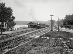 Circa 1906. "Railway station at Weirs -- Lake Winnipesaukee, New Hampshire." 5x7 inch dry plate glass negative, Detroit Publishing Company. View full size.
Still there!The station is still in use, selling tickets for cruises on the lake and for the scenic railroad trips that use these same tracks. 
Now with ample parking:

A statue in the street?Is that a statue of a soldier leaning on his rifle directly in front of the speeding buggy, or a gas lamp hanging from the pole in the foreground?
[Looks like a water fountain with provision for horses. A common kind of street furniture of the period, though not always as fancy. -tterrace]
Civil War monumentSpent many happy days at the Weirs as a child. The 19th ct Mt. Washington still plies the lake. The Civil War monument and horse trough was located in front of the NH veterans home in the 1880s and was unfortunately struck by lightning and destroyed in the 30s.
WaterThe name Winnipeg (the city where I was born) comes from both Cree and Ojibwe words for dirty or murky or muddy (wini) and water (nipi).  Winnipesaukee is from the Abenaki language and is translated as the Smile of the Great Spirit but also Beautiful Water in a High Place or Good Smooth Water at Outlet.  I favor the water option.  And I suppose one person's murky is another person's beautiful.
Shorpy&#039;s Guide to NH tourist traps continues!First Market Square, now The Weirs.  Is Monadnock next?
To clarify a previous post by nhman, the "19th ct" Mt Washington burned in 1939.  The current Mt Washington II started life in 1888 on Lake Champlain.   They chopped it up, put it on rail cars, and welded it back together at Lakeport to replace the burned out Mt Washington.  Still pretty neat.
And now that I'm fact checking it... The train station burned down at the same time.  So I'm not so sure Hillary's street view is the same building.
Still there but notThis is not the same building as the original picture. When the Mount burned at the dock the Depot building of that time was lost where the fire consumed the dock leading from the depot.  This building that replaced that building was removed some time in the last 20 years. 
ID&#039;ing the locomotiveI'm guessing that this is a Boston &amp; Maine class C-17 4-6-0, based on the side view seen partway down this page.
Lovely engine.  My favorite locos by far are the high-wheeled passenger 4-6-0s and 4-4-2s from the early 20th century.
(The Gallery, DPC, Railroads)