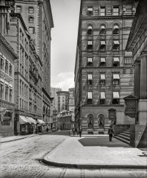 Boston, Massachusetts, circa 1906. "Court Street, Ames Building, Young's Hotel." Plus a subway entrance. 8x10 inch glass negative, Detroit Publishing Company. View full size.
Court StreetI love this photo, I know this area and it's its history well.
The Ames Building is still there, the adjoining building, with three facades is still there, but only underground.  In the 1920's, the building was gutted and a Bank was built.  It later became a Veterans Administration Clinic and in 1993 The New England Shelter for Homeless Veterans.  If you were to go in the sub-subbasement of of NESHV, you wold see the original foundation of the 1906 building.
The building on the right, marked East Boston Tunnel, was the original site of the beginning of the Blue Line, which ran from Court Street to now Maverick Station.  The East Boston Tunnel was the first subway in the world to run underneath a section of the ocean. It was built in 1904.  The building is still there and houses Boston's Department of Neighborhoods.
On a side note, the fare from Court Street to Maverick was 1 cent.
Old State HouseMost of the buildings shown here are gone. The Ames building, on the left, is now a hotel. The two closest buildings on the right are gone and the small building down the street is the Old State House, famous for being the site of the Boston Massacre. On March 5 it will be the site of the annual reenactment.
East Boston TunnelActually, I believe the building on the right (with the East Boston Tunnel signs) is still extant, just with some modifications.
The East Boston Tunnel used to be the terminus of a streetcar line that was the first to pass under the ocean. It is now the Blue Line subway, and the Court Street station pictured here was closed in 1916 when the terminus was moved to Bowdoin Street. You can see from the vents that the tunnel still passes below this location today.
Old State HouseI didn't even realize that was the Old State House until I looked closer. I had thought the English monarch's unicorn and (unseen here) lion had been added during a later restoration, but it seems they were placed there in the 1882 reconstruction. At least the building is in great shape today, though it is now surrounded by glass towers instead of stately stone buildings.
Green and OrangeThe two buildings immediately behind the Old State House are still there.  Behind those buildings, however, is a new (1990s) glass skyscraper.  So from this angle, you can now see an 18th century building, in front of a couple of 19th century buildings, which are in front of a 20th century building.  Makes for an interesting photograph.  Today there isn't a subway entrance exactly where the one depicted in the photograph is.  I'm guessing it was for the Green Line, which today has a station at Government Center, essentially behind the Ames Building.  The Orange Line has a station right below the Old State House, but I don't think there was an Orange Line in 1906.
Great picture!!
Traffic postJust in front of the Old State House are the intersections
of Court, State, New Congress and Washington streets. That was my old traffic post when assigned to the now defunct Traffic Division of the Boston Police Department. As an aside, the State Street subway entrance was built right into the lower section of the Old State House. The historical significance of the building meant nothing.  
+107Below is the same view from June of 2013.
(The Gallery, Boston, DPC, Streetcars)