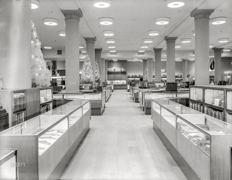 November 11, 1950. New York. "Gimbel Brothers department store. Interior. Raymond Loewy Associates, architect." 4x5 inch acetate negative by Gottscho-Schleisner. View full size.&nbsp;
A street floor named desire
&nbsp; &nbsp; &nbsp; &nbsp; Ah for the infinite loveliness of Gimbels. We're the most enticing, most alluring street floor that ever walked the ways of beauty. So captivating are we, you just can't resist us. Our walls are delicately tinted. Our counters are sleek. If we were a bell, we would tinkle. We're all this, and more, because Raymond Loewy, genius at transforming an ugly duckling into a raving beauty, has given us his magic touch. And the best part is, this beauty of ours will be a joy forever. Our loveliness will never pass into nothingness. Why? Because those sweet, sweet bargains and those low, low price tags keep coming and coming and coming ... (NYT ad, Feb. 1951)